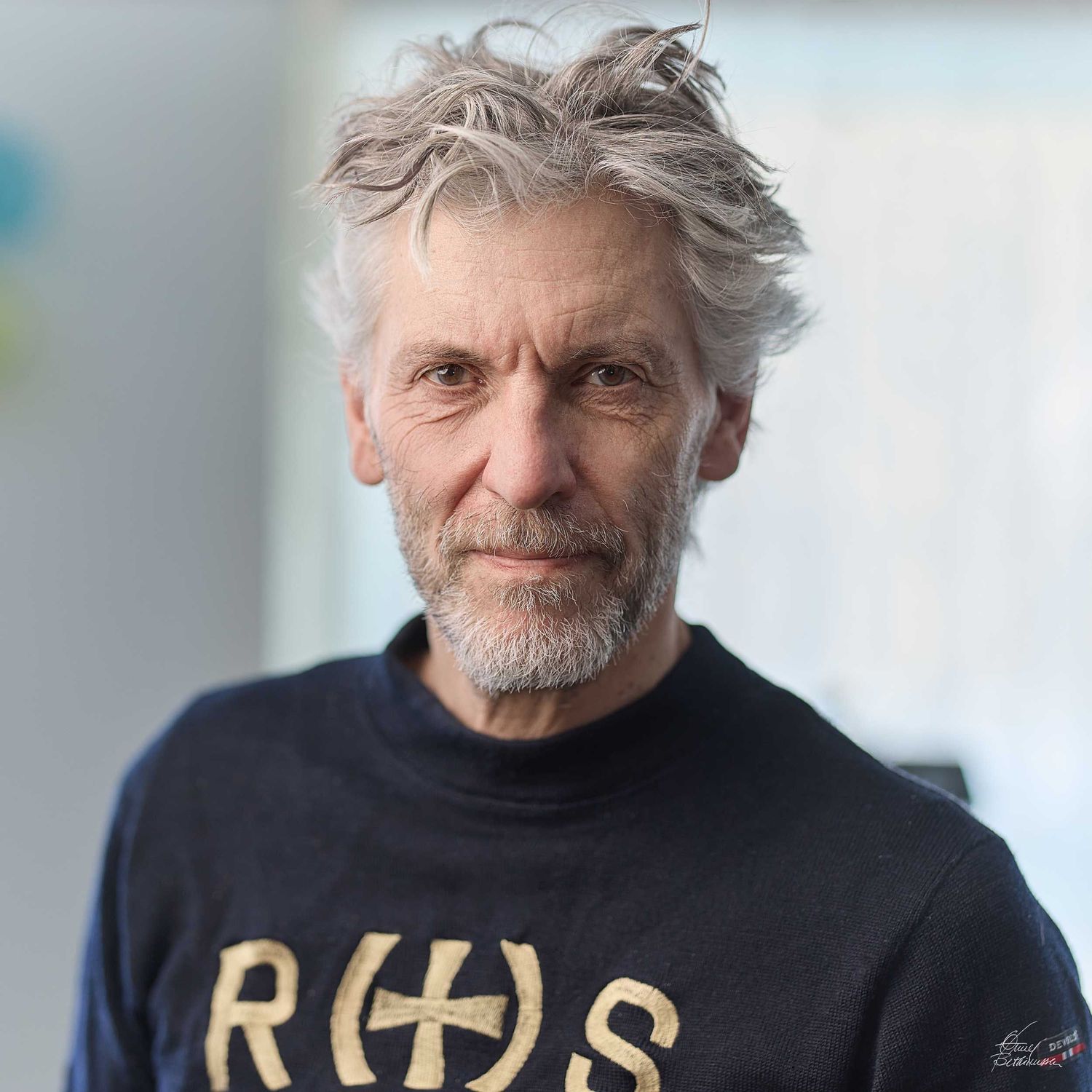 Person wearing a dark sweater with gold text against light background.