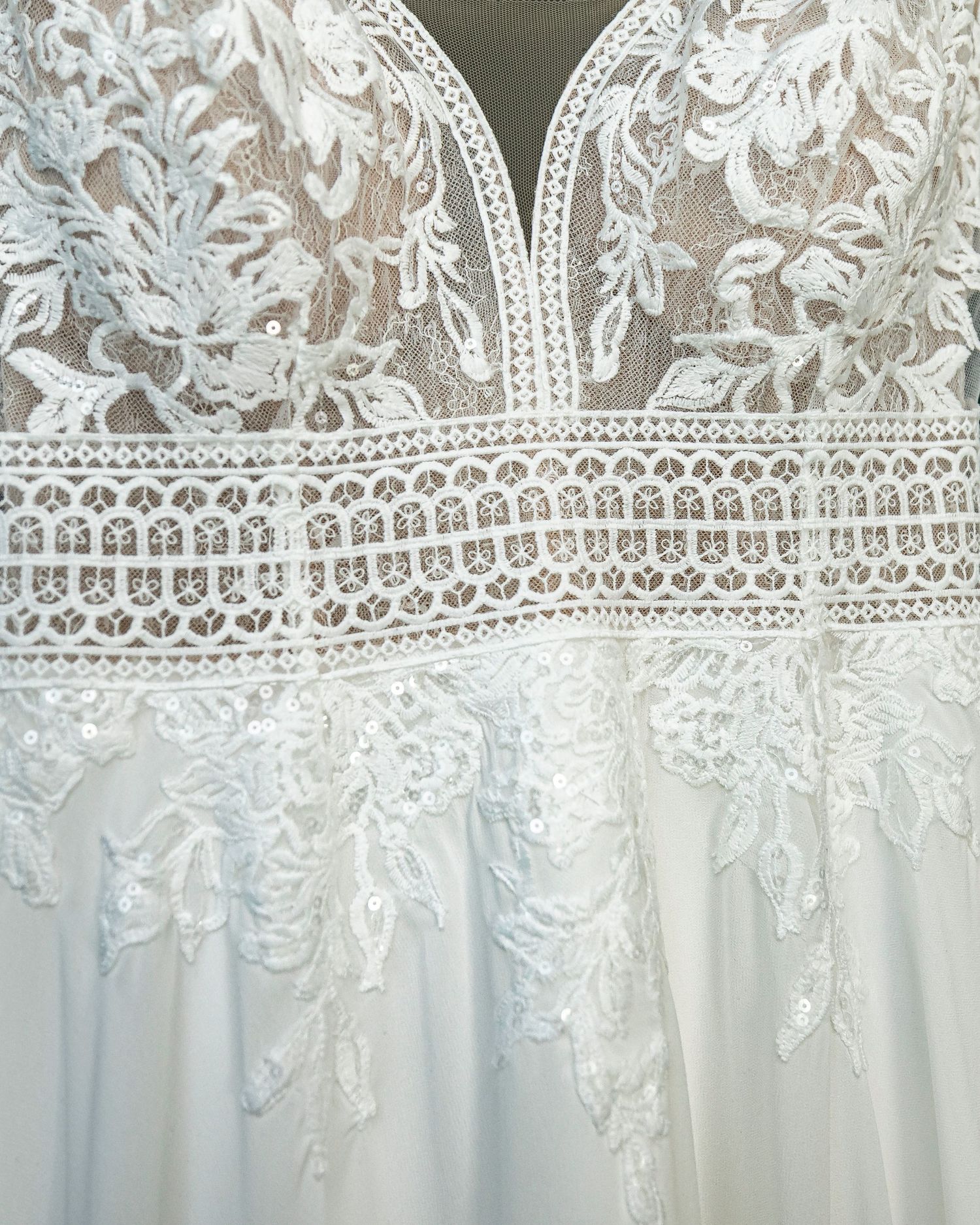 Delicate white lace trim detail with floral patterns against a light background.