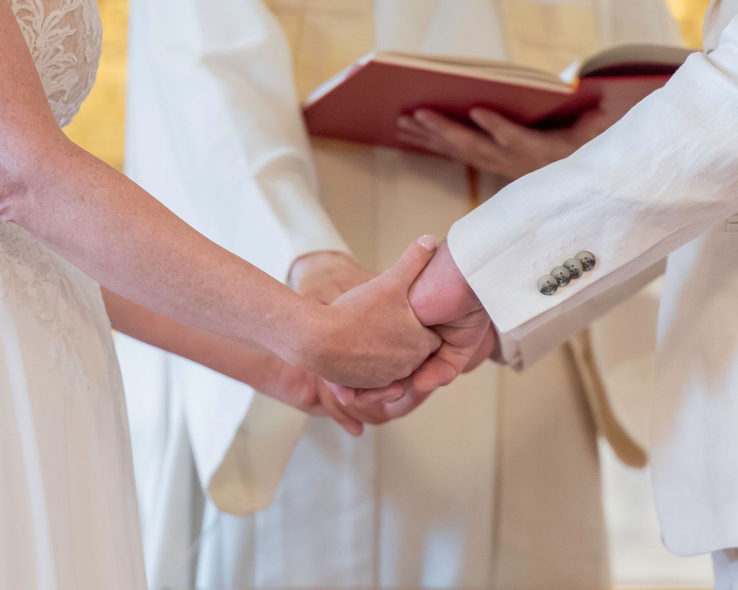 Two hands hold a white cloth or fabric in close-up view, appearing to be part of a ceremony or ritual.