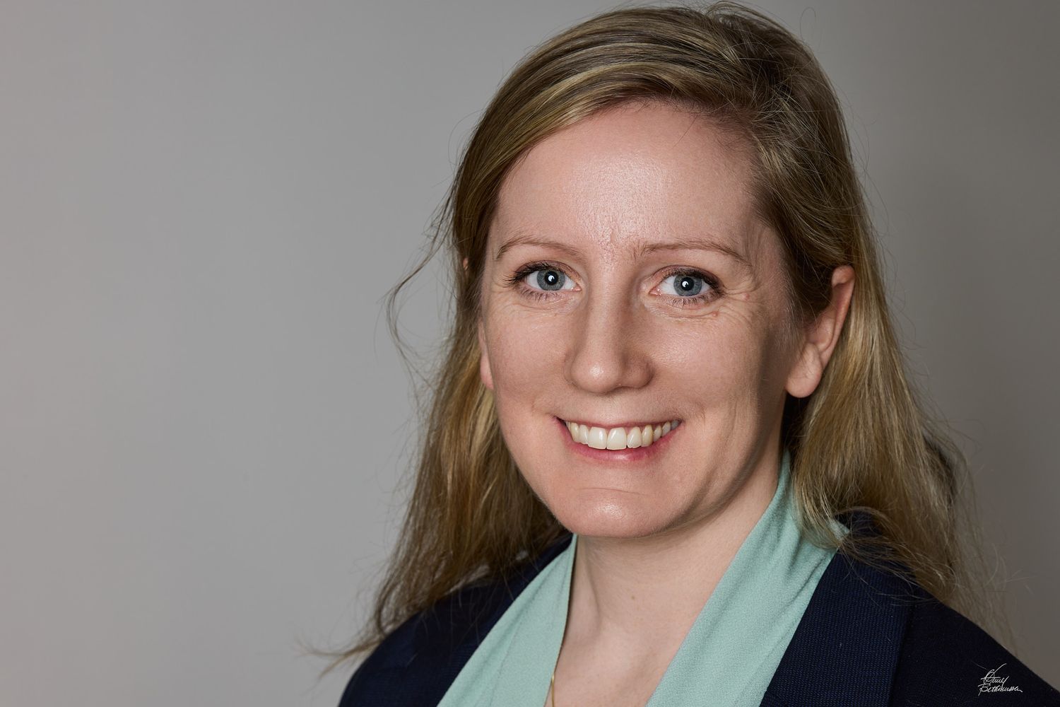Professional headshot photos of a person in business attire against a neutral background.
