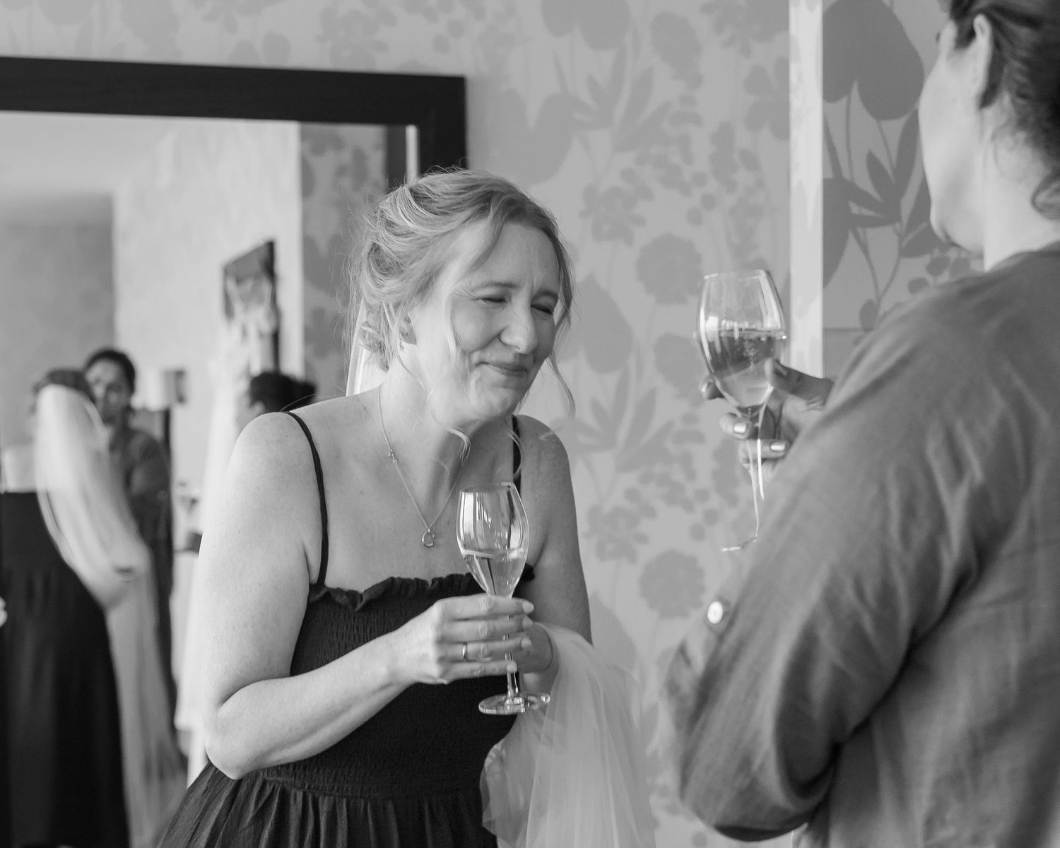 A series of black and white candid photos showing people holding wine glasses and socializing at an event.