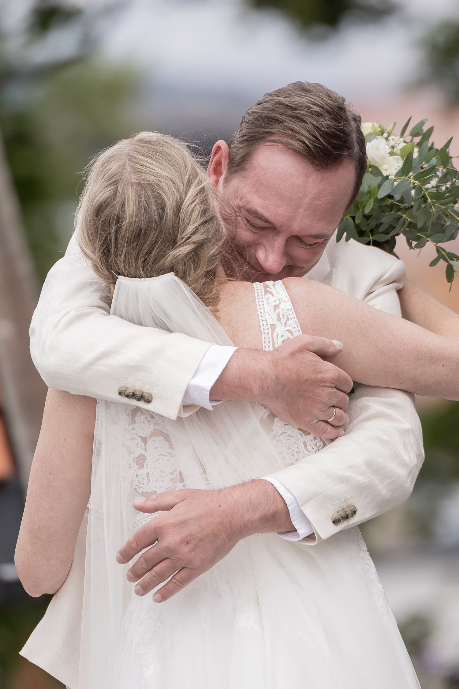 Romantic wedding couple sharing tender embraces in a sequence of emotional first look moments outdoors.
