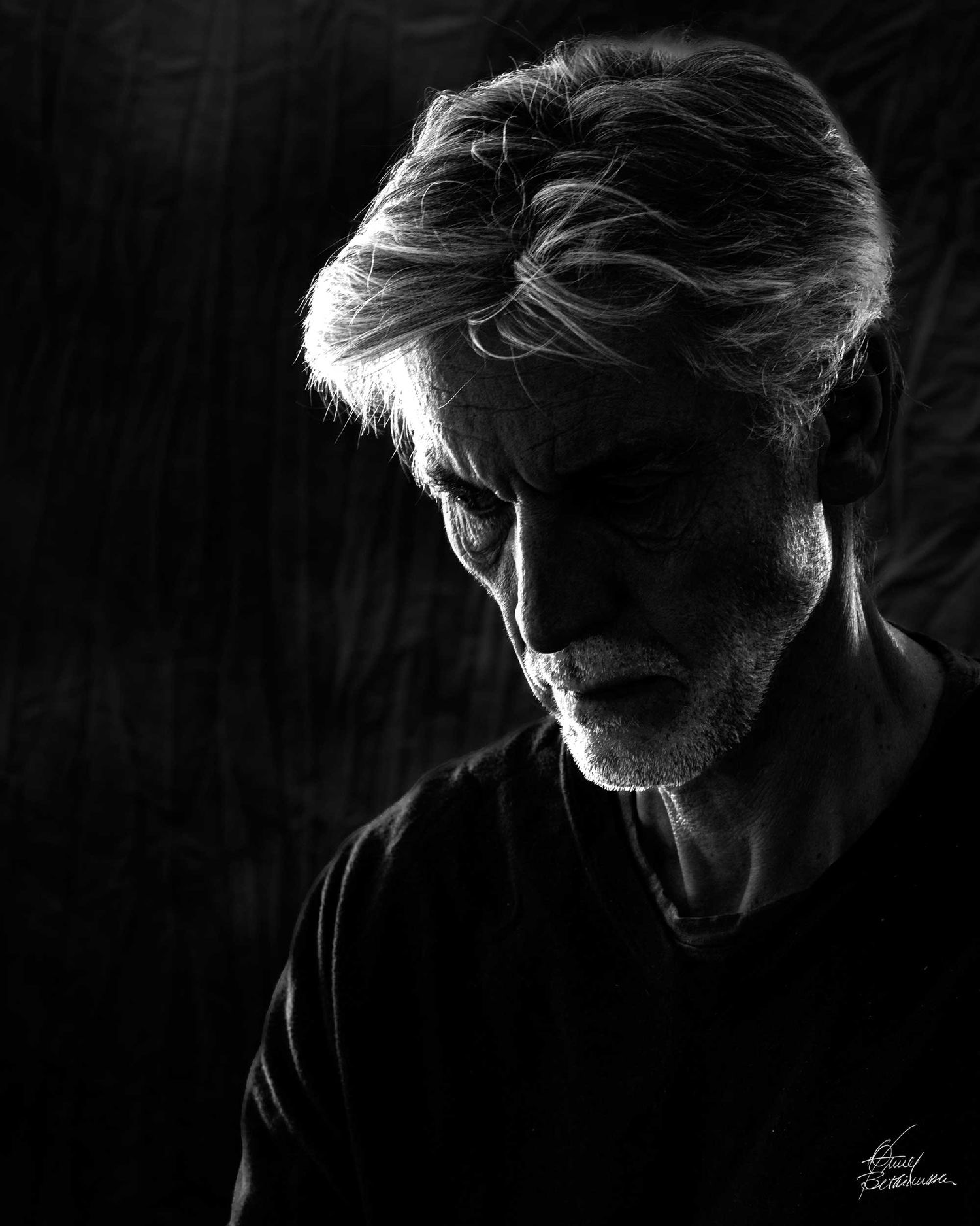 Dramatic black and white profile portrait with strong side lighting.