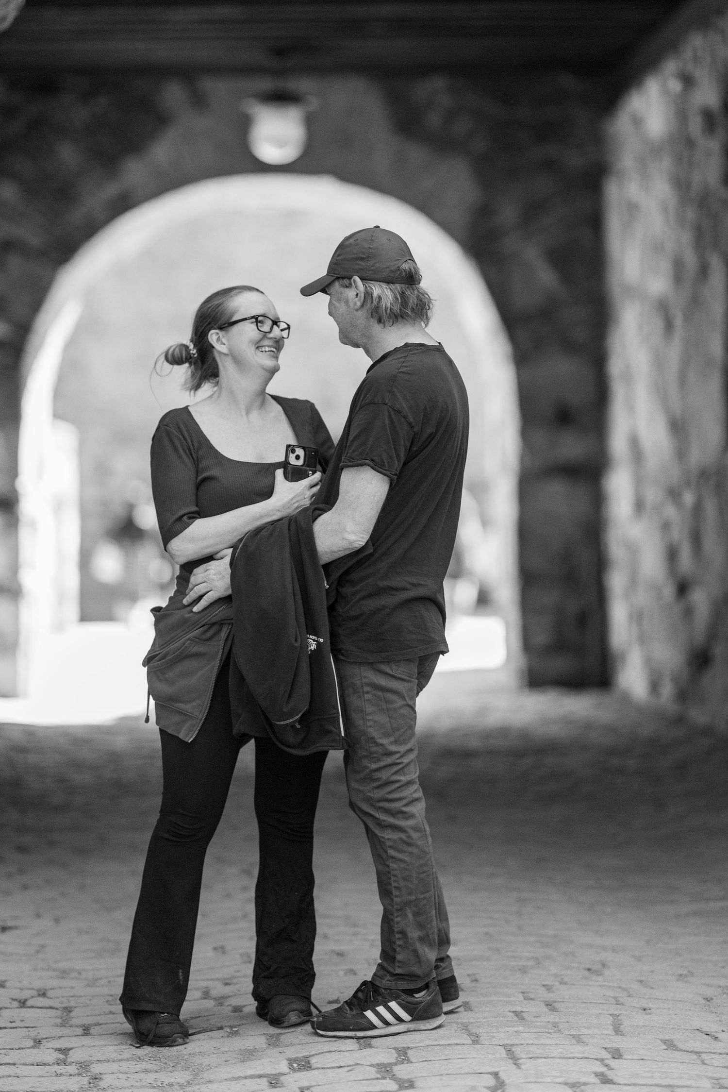 Black and white sequence shows a tender moment between two people in an arched passageway.