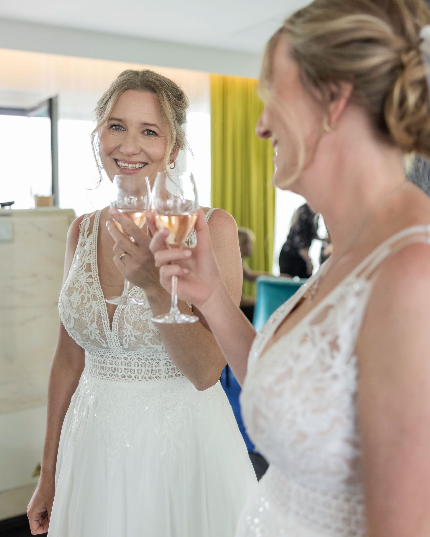 Wedding celebration showing joyful moments between two people in elegant white attire sharing drinks and laughter.
