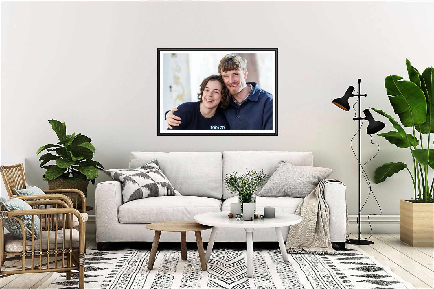 Framed photo of a smiling couple displayed above a white sofa in a modern living room with plants and patterned rug.