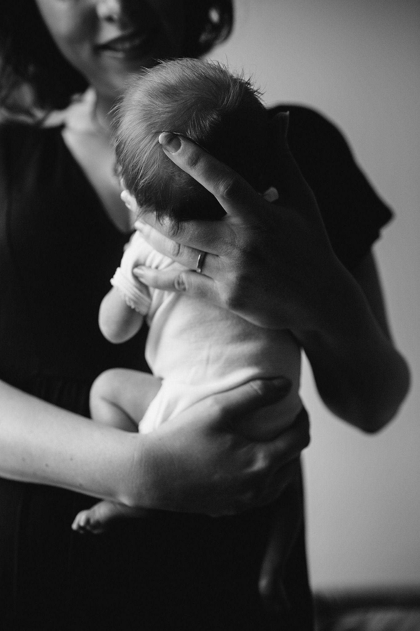 A black and white portrait of a parent cradling a small baby
