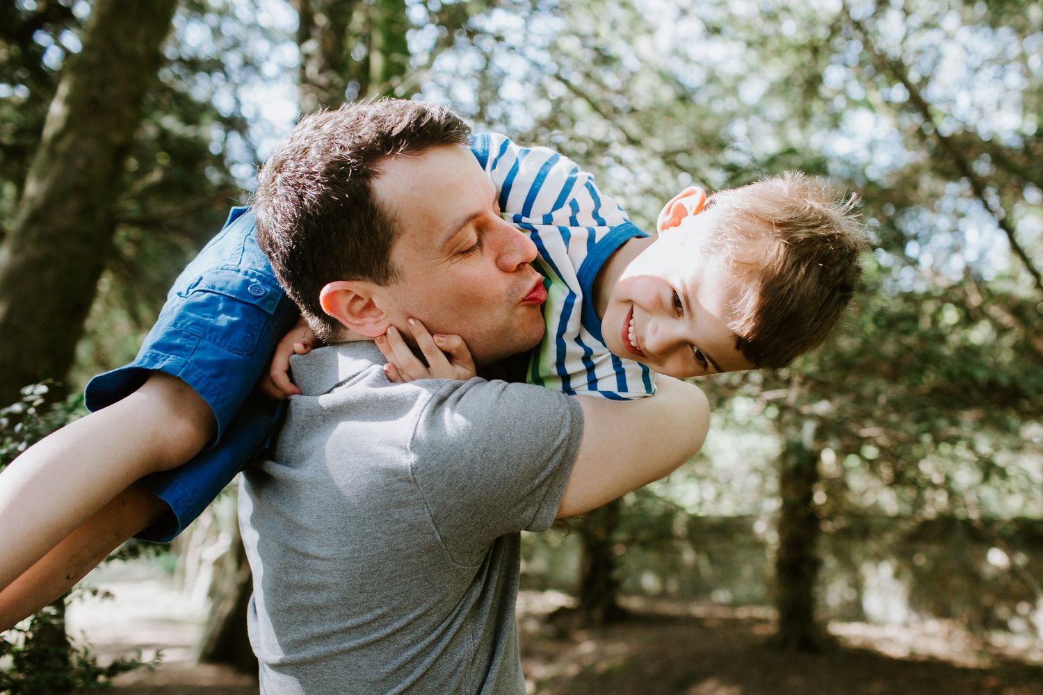 Playful moment between parent and child in a wooded setting.