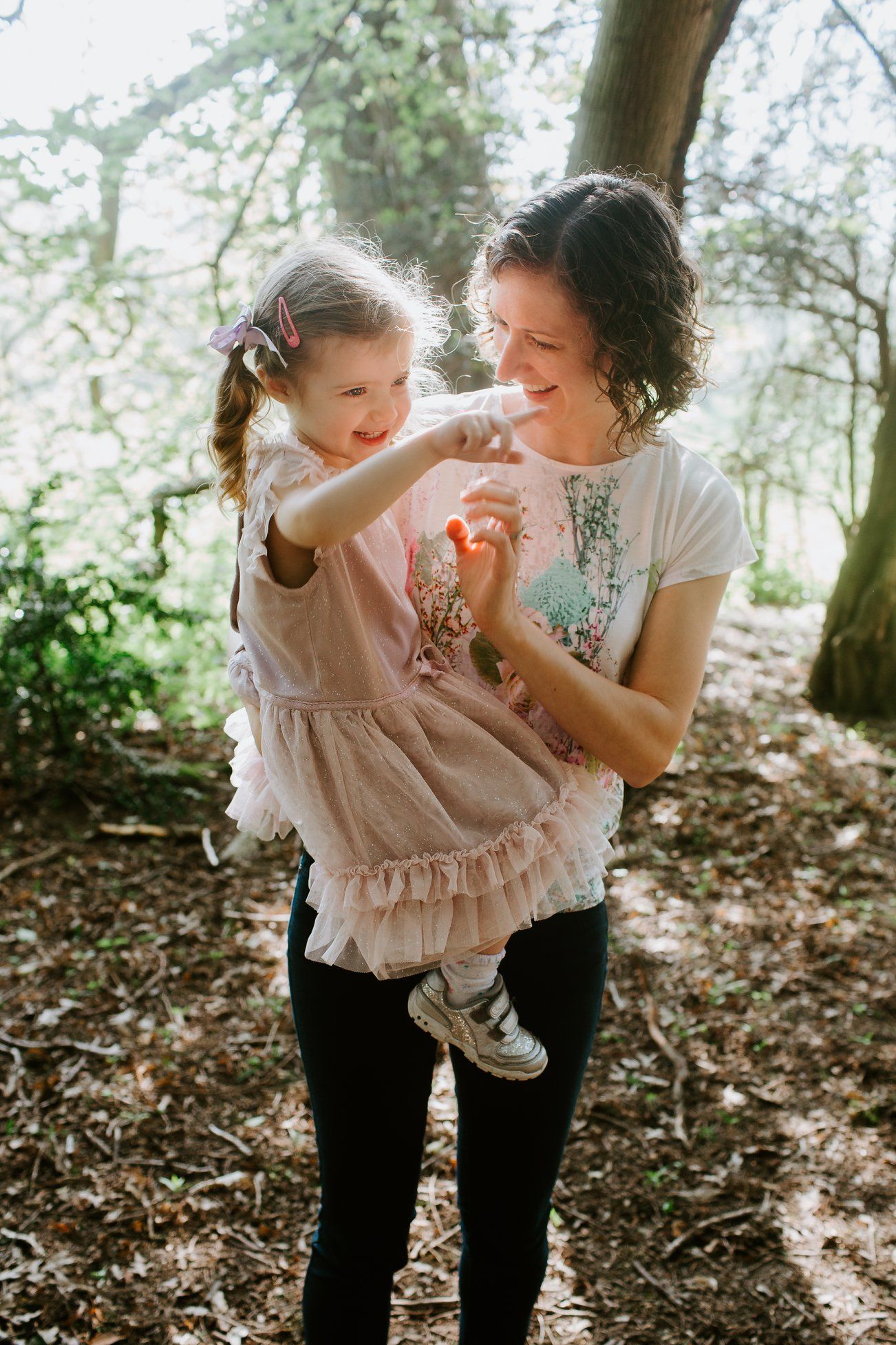 Playful interaction between two people under blooming trees in dappled sunlight.