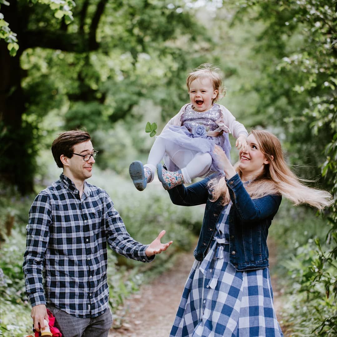Candid family moments captured in a lush green woodland setting.