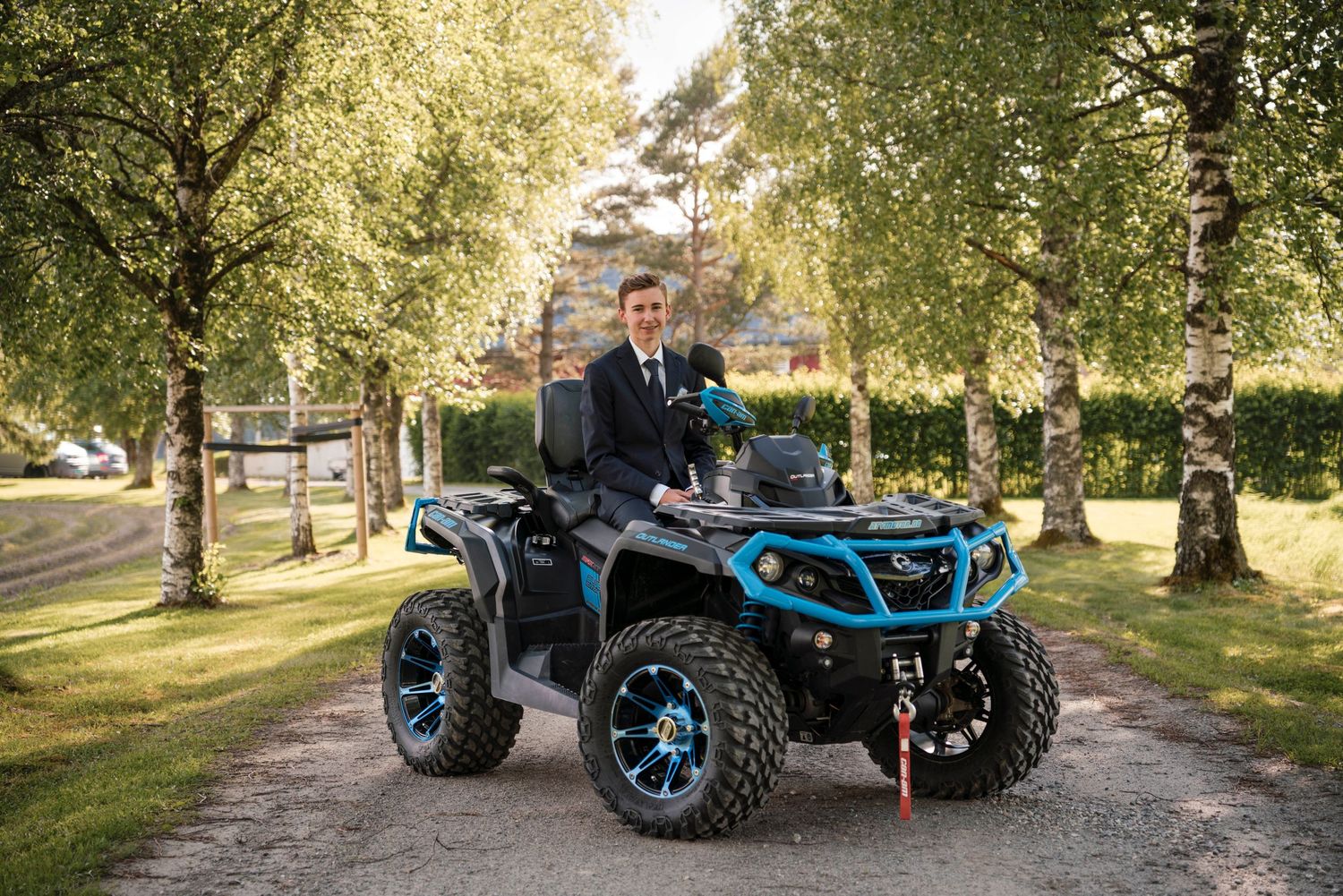 A blue-trimmed ATV parked on a tree-lined path during golden hour.