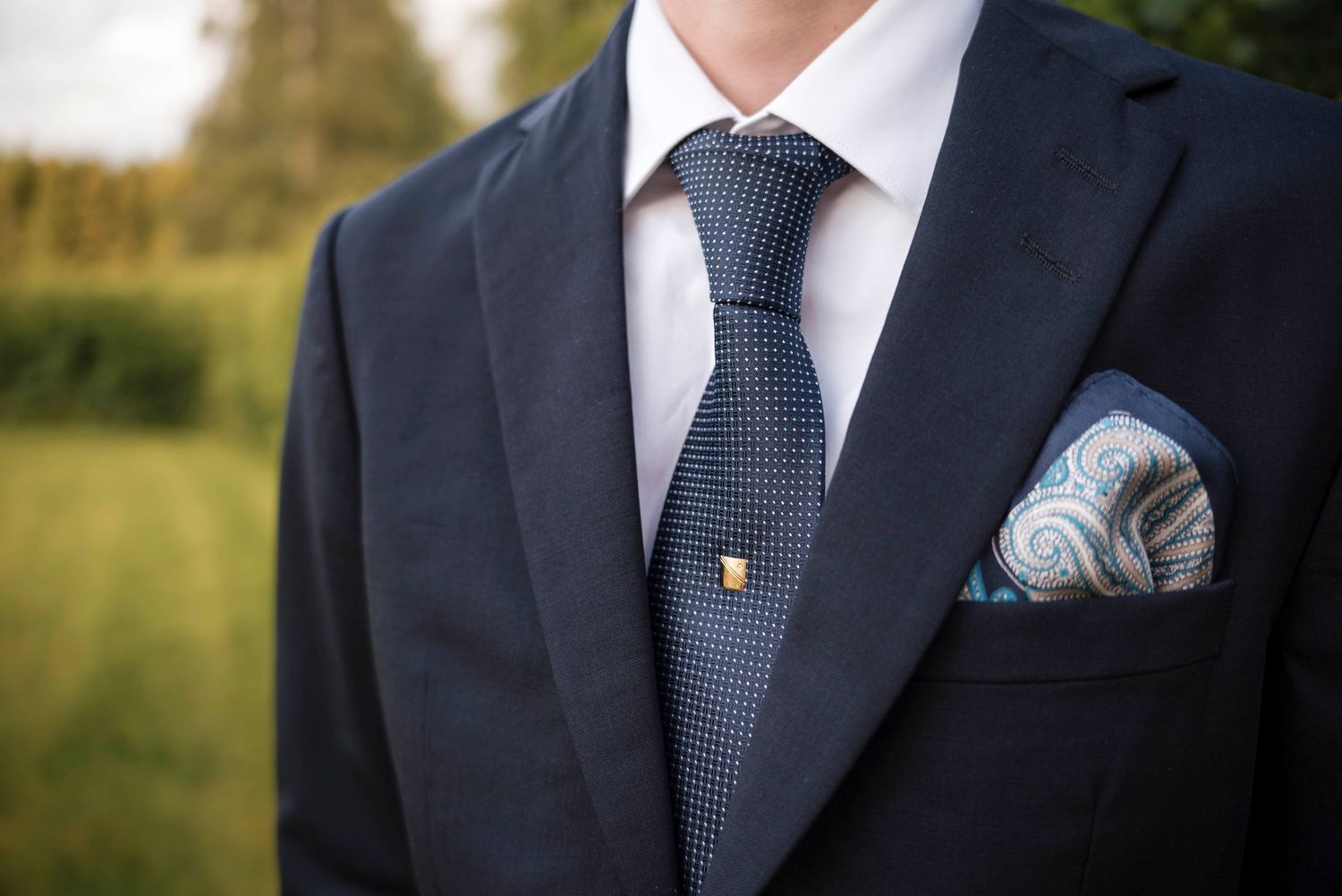Close-up details of navy blue suit jackets and ties at a formal event.
