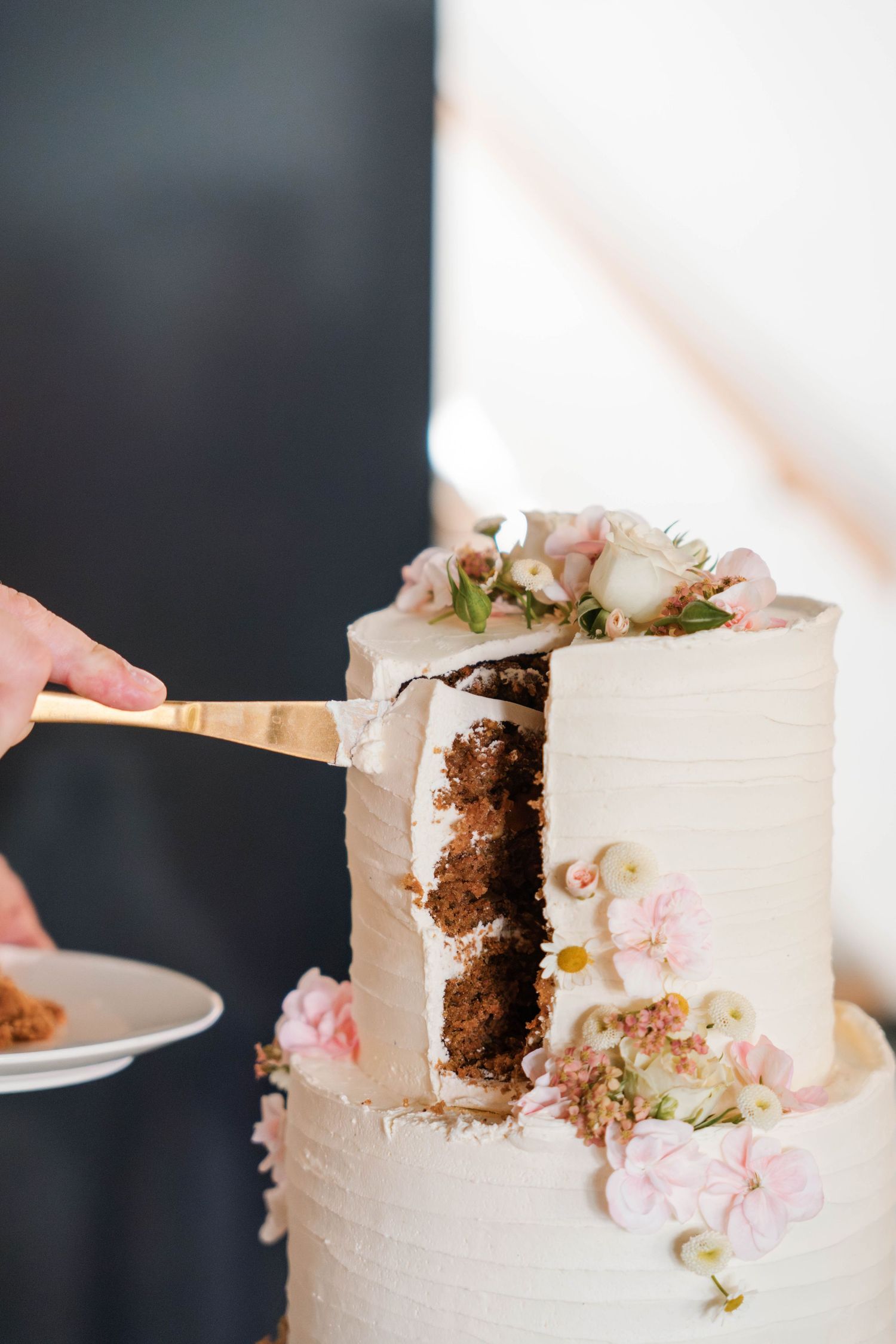 Four sequential photos showing slices being cut from a white frosted cake decorated with delicate pink flowers.