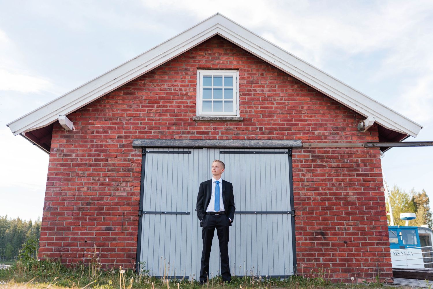 A rustic red brick barn with gray doors photographed from different angles.