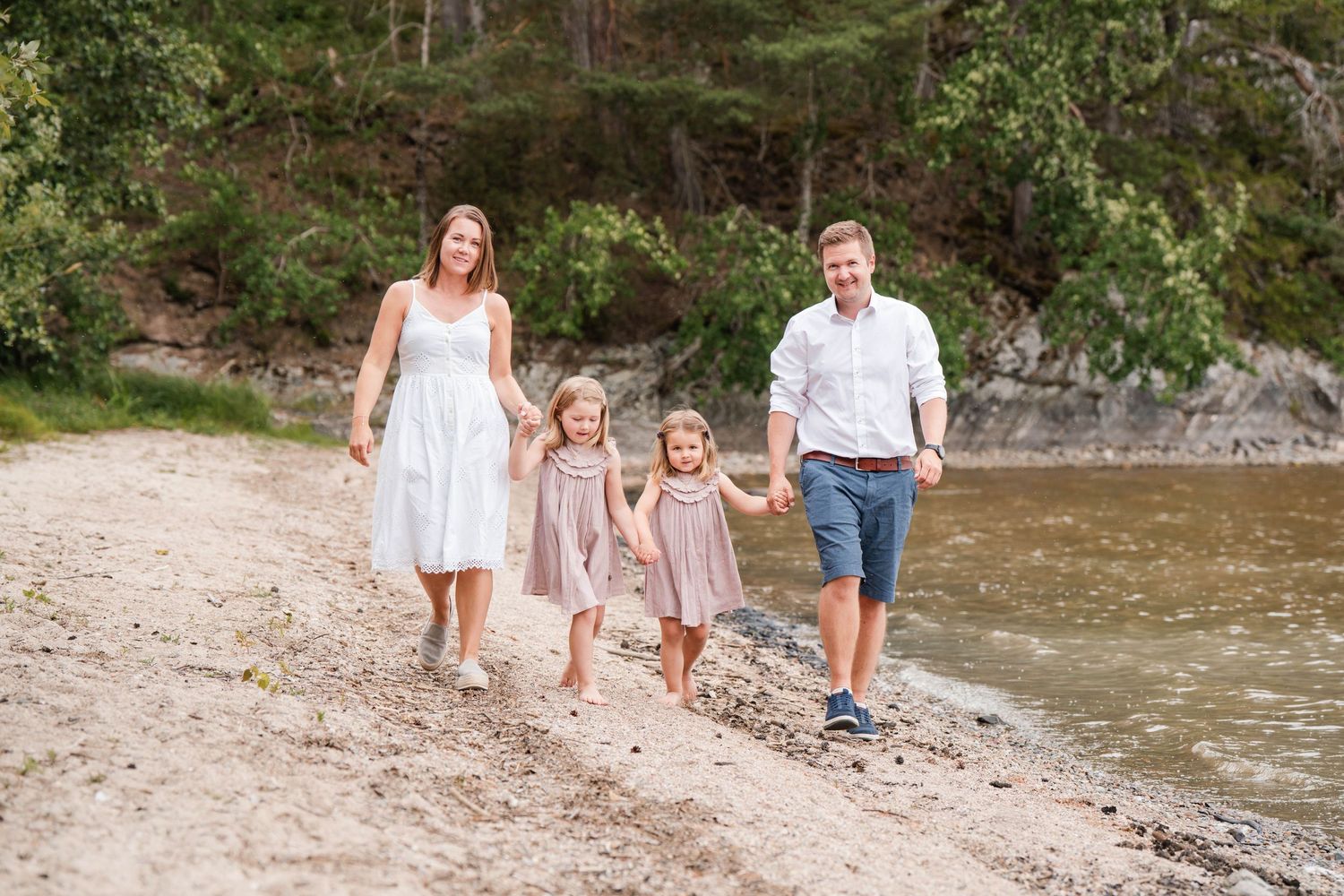 Family strolling along a rocky riverbank surrounded by natural scenery.