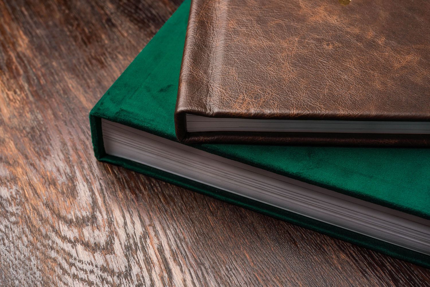 Close-up view of a leather-bound photo album with dark brown textured cover on wooden surface.