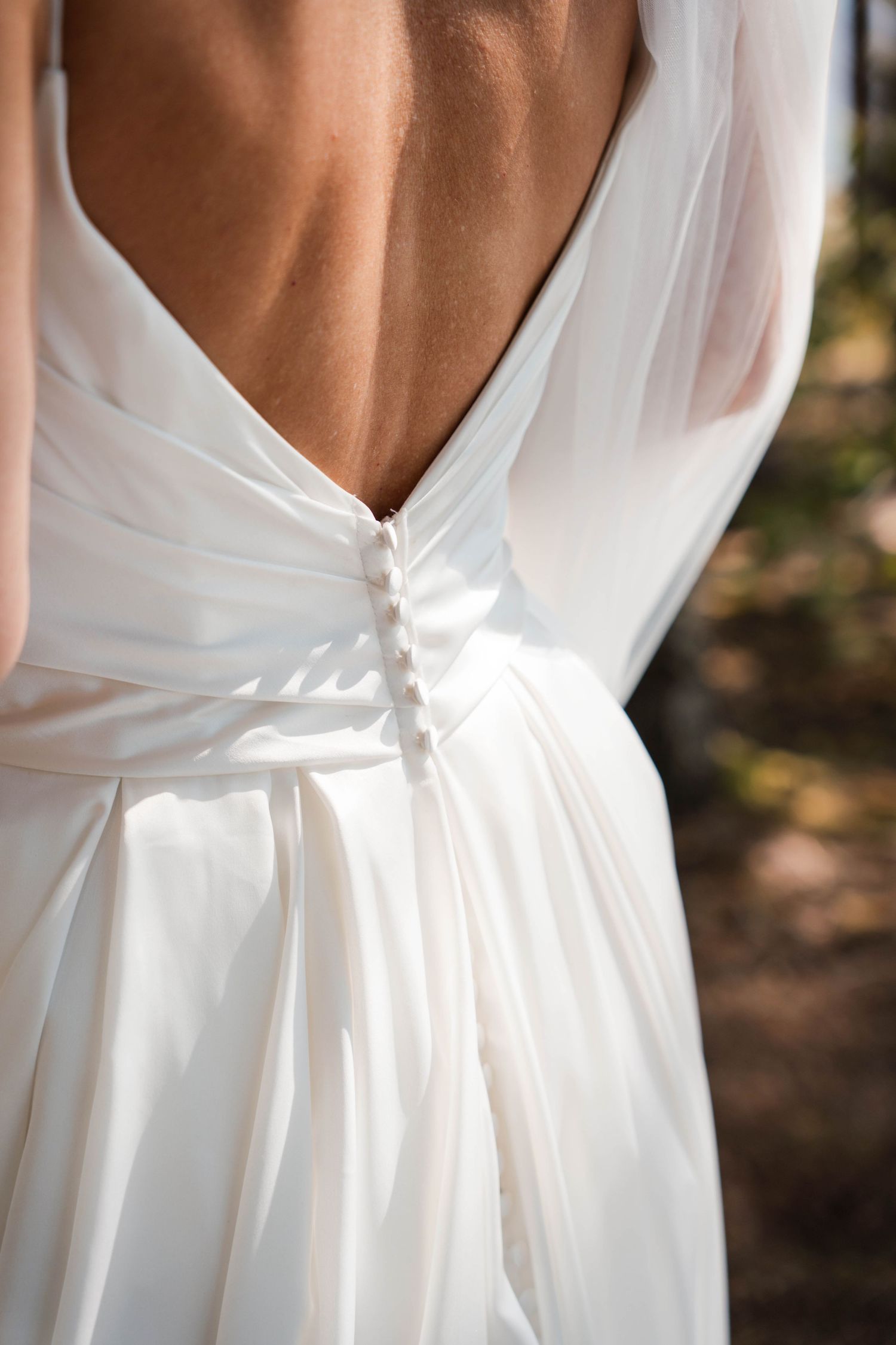 Close-up details of a white wedding dress showing elegant back design and fabric draping.