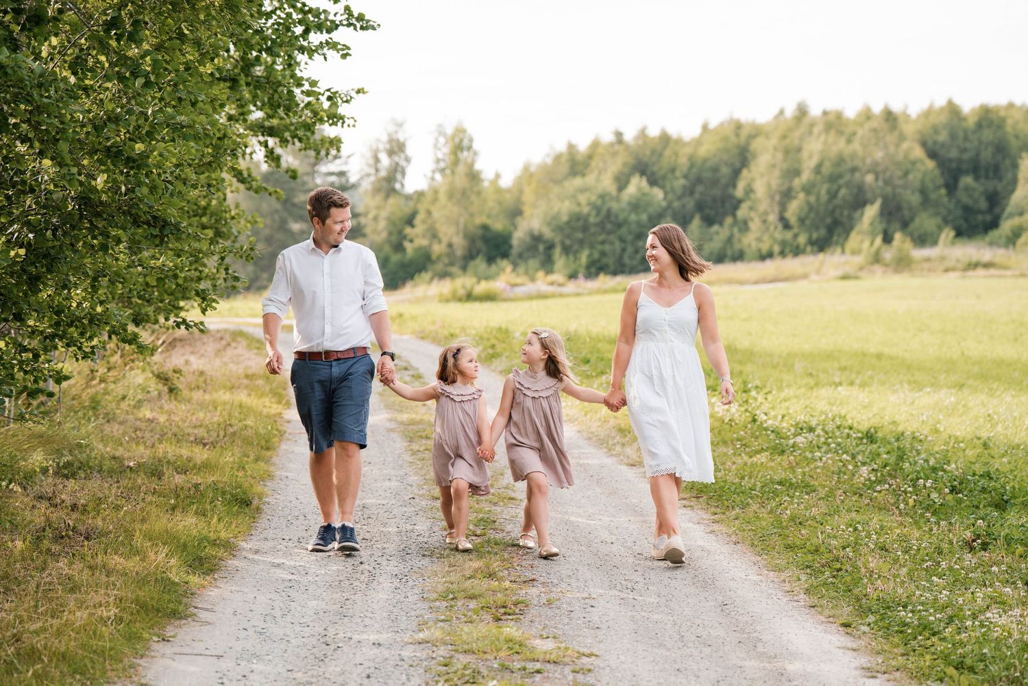 A family walks hand in hand down a country path on a sunny summer day.