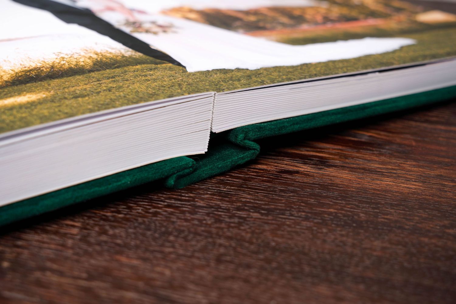 Close-up detail of a professional photo album binding showing layflat pages with green spine.