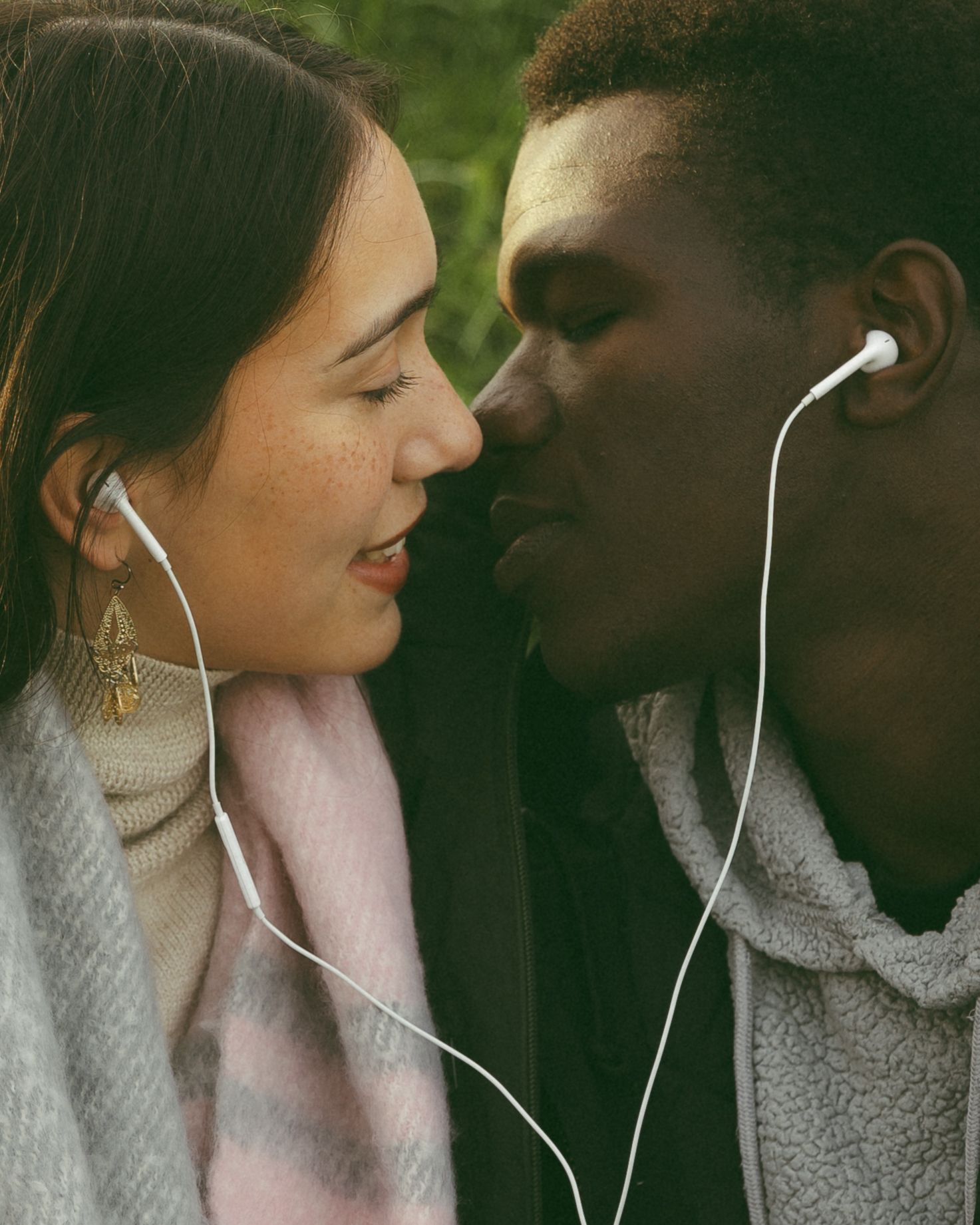 Intimate close-up of couple sharing earbuds while listening to music together.
