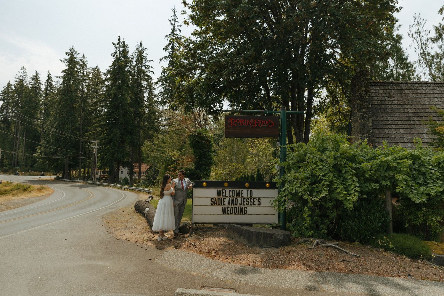 A panoramic view of a tree-lined path with buildings visible in the background on a sunny day.