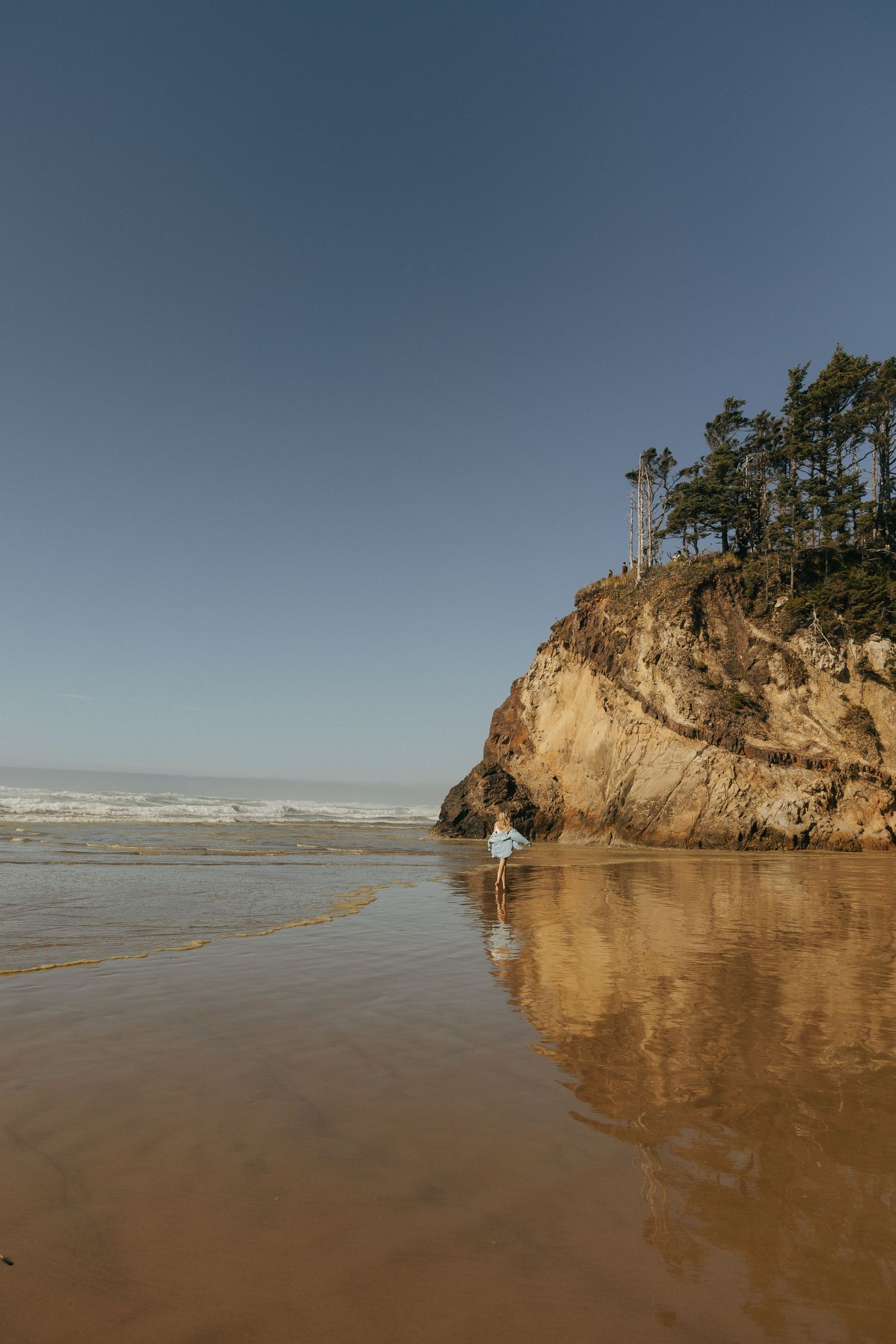 Dramatic coastal landscape with rocky cliffs and sandy beach during golden hour.