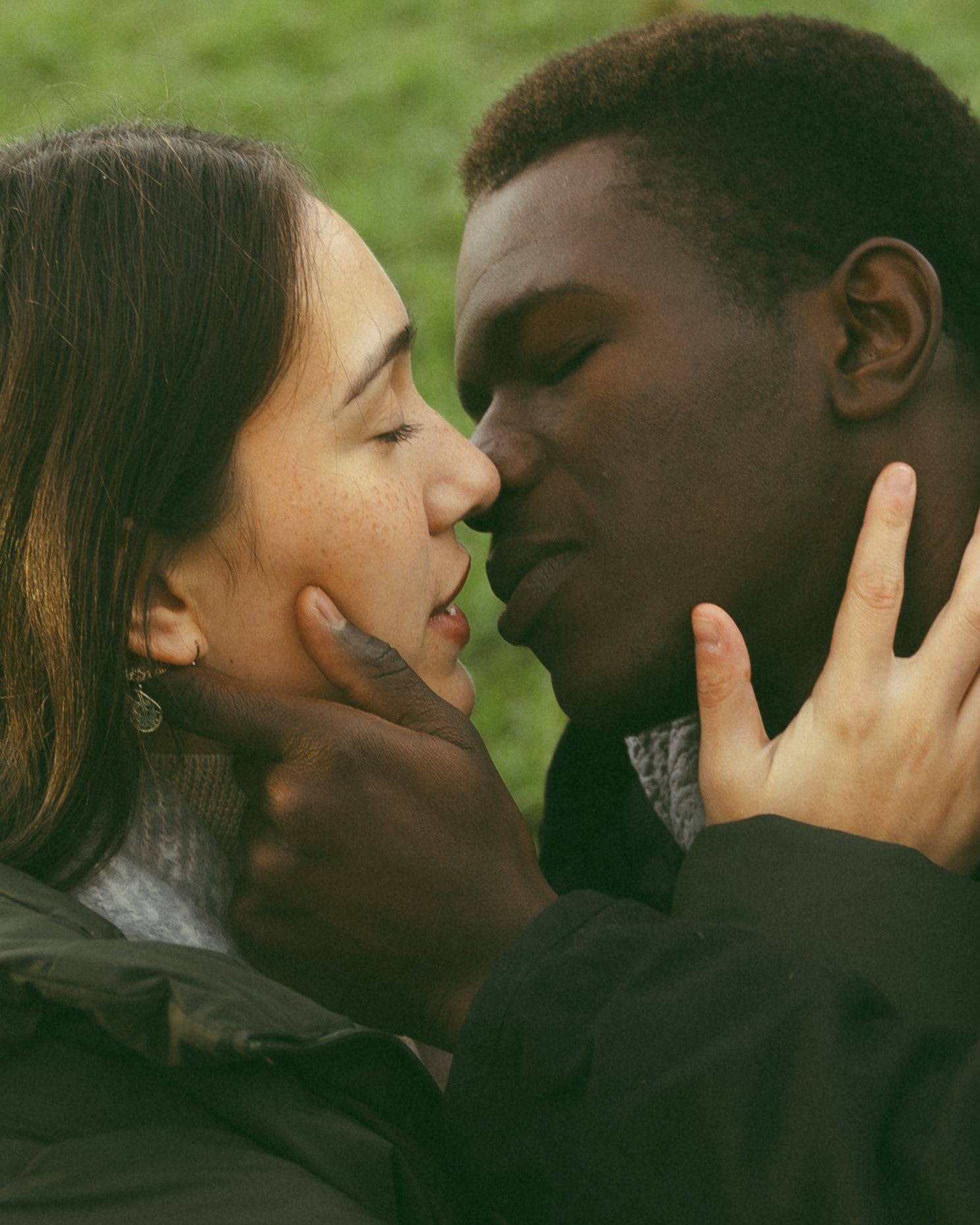 Intimate close-up of a couple sharing a tender moment against a green background.