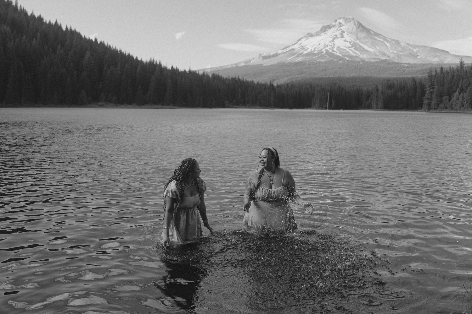 Two girls playing in Trillium Lake with snow-capped Mt. Hood in background.