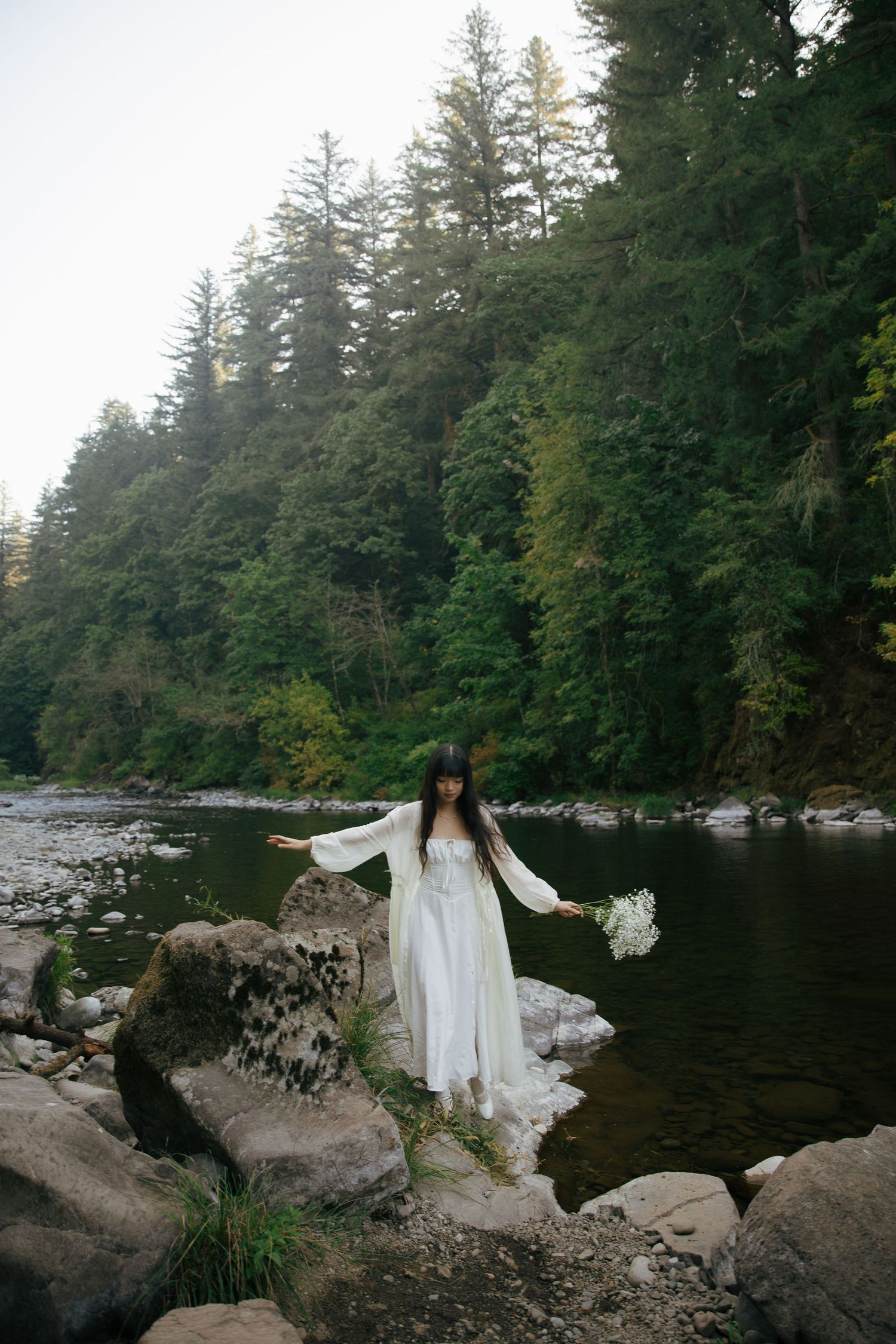 Serene lake surrounded by tall evergreen trees with rocks along the shoreline.