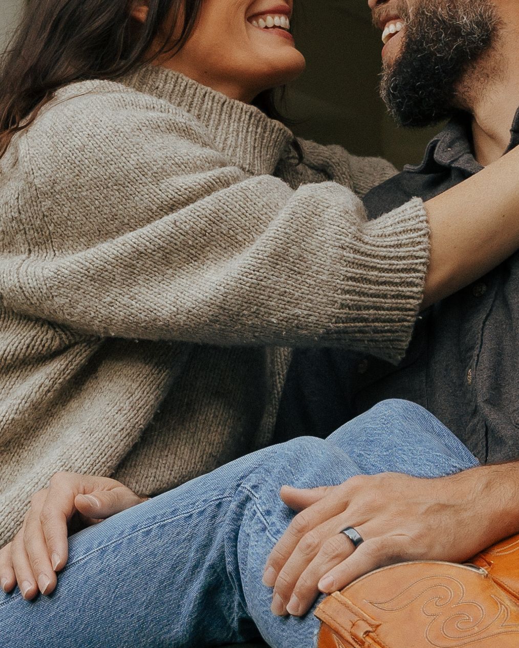 A couple sharing an intimate moment while sitting together in casual sweaters and jeans.
