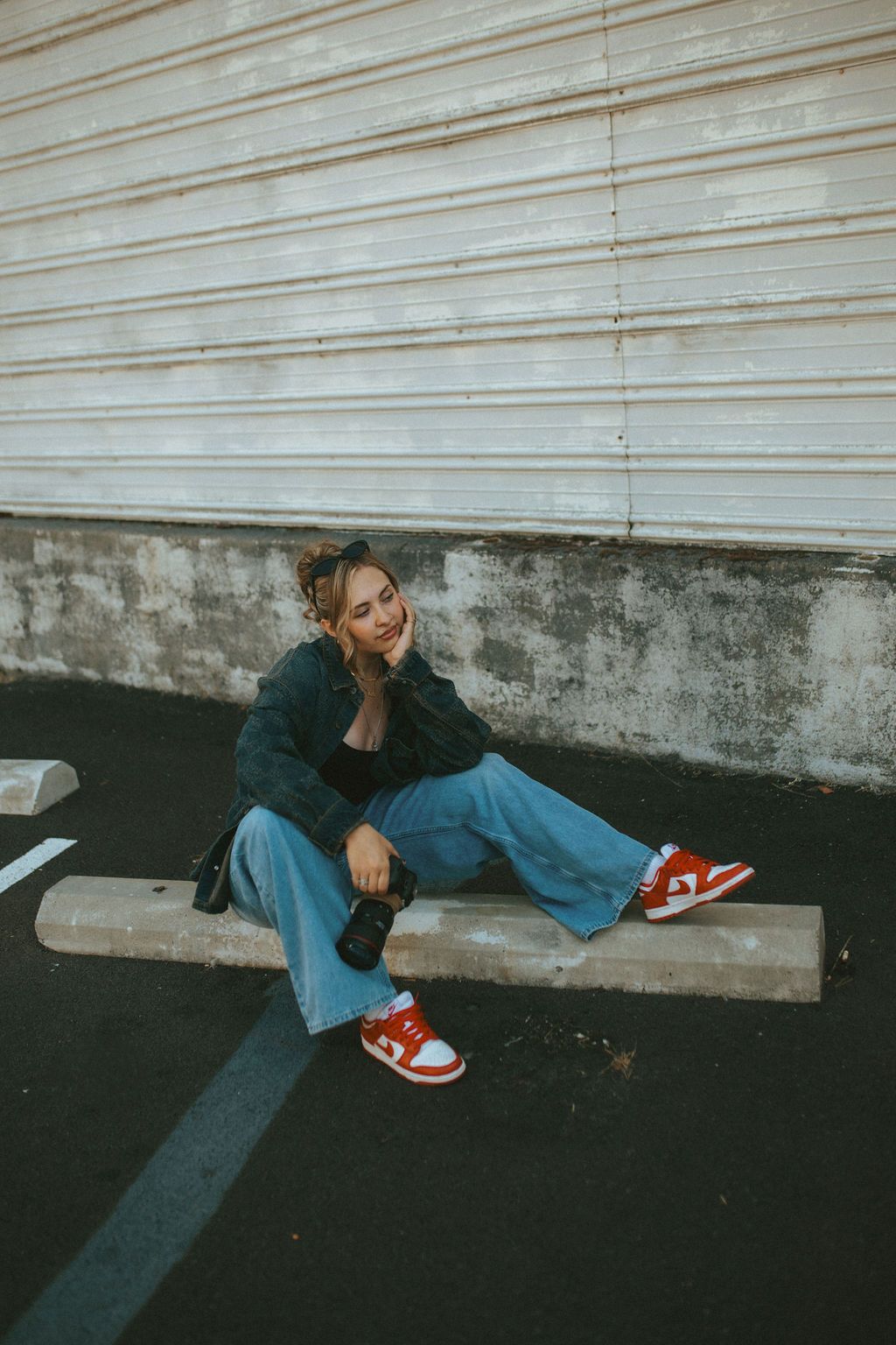 Artistic fashion poses on ground with white industrial wall and red footwear.