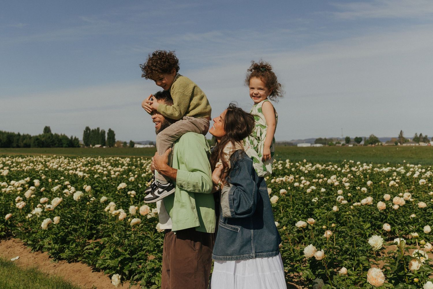 People exploring and gathering flowers in a vast field under blue skies.