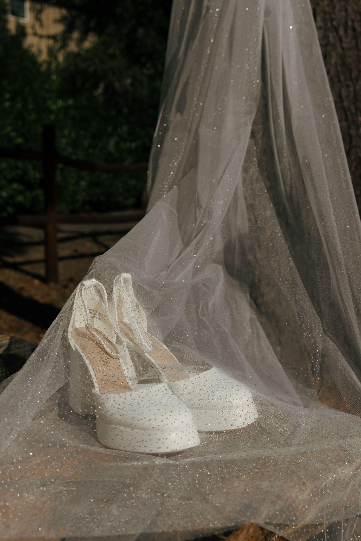 A sequence of close-up shots showing delicate white bridal shoes with sparkly details under a flowing tulle veil.