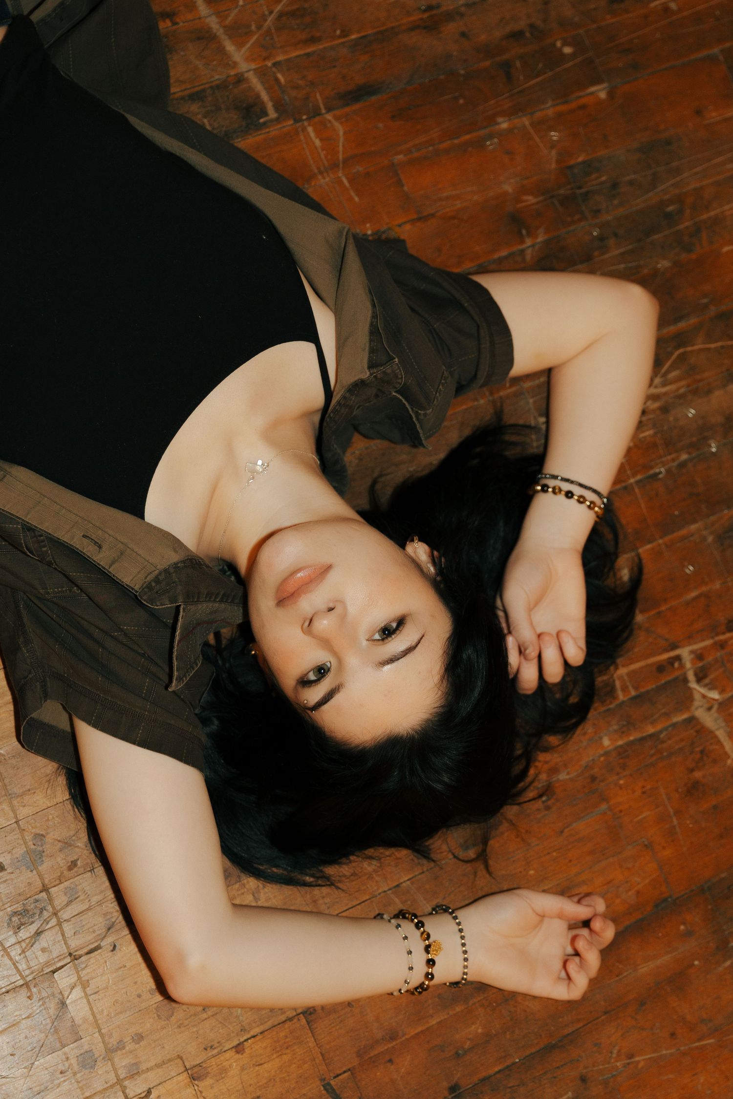 Artistic portrait on wooden floor with dramatic lighting and dark tones.