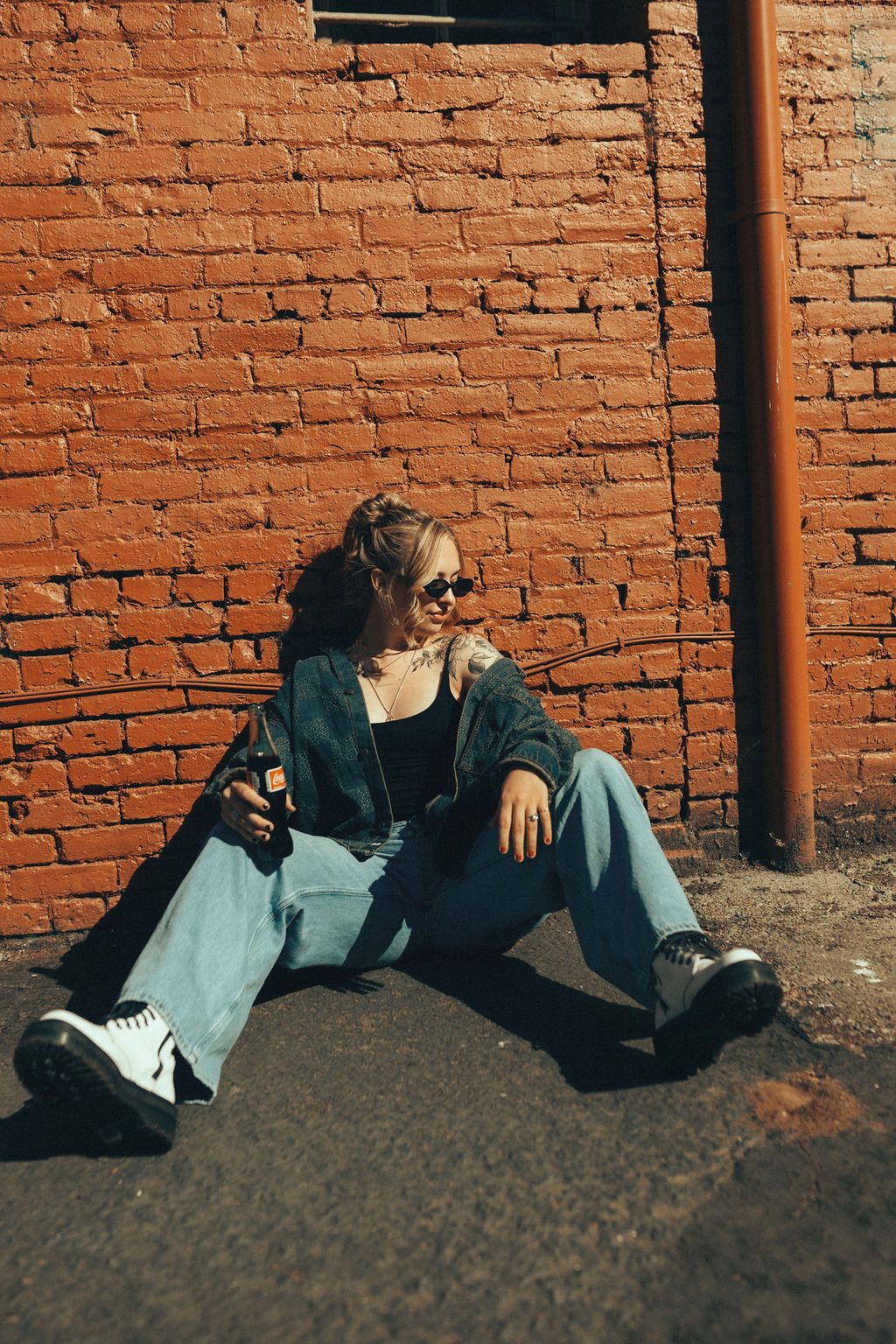 Moody fashion portraits against rustic brick wall in natural lighting.