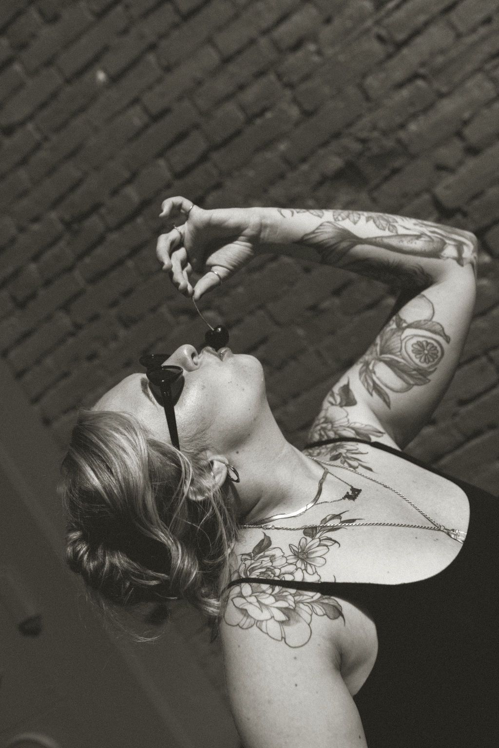 Artistic black and white portrait of person with tattoos looking up dramatically against textured background.