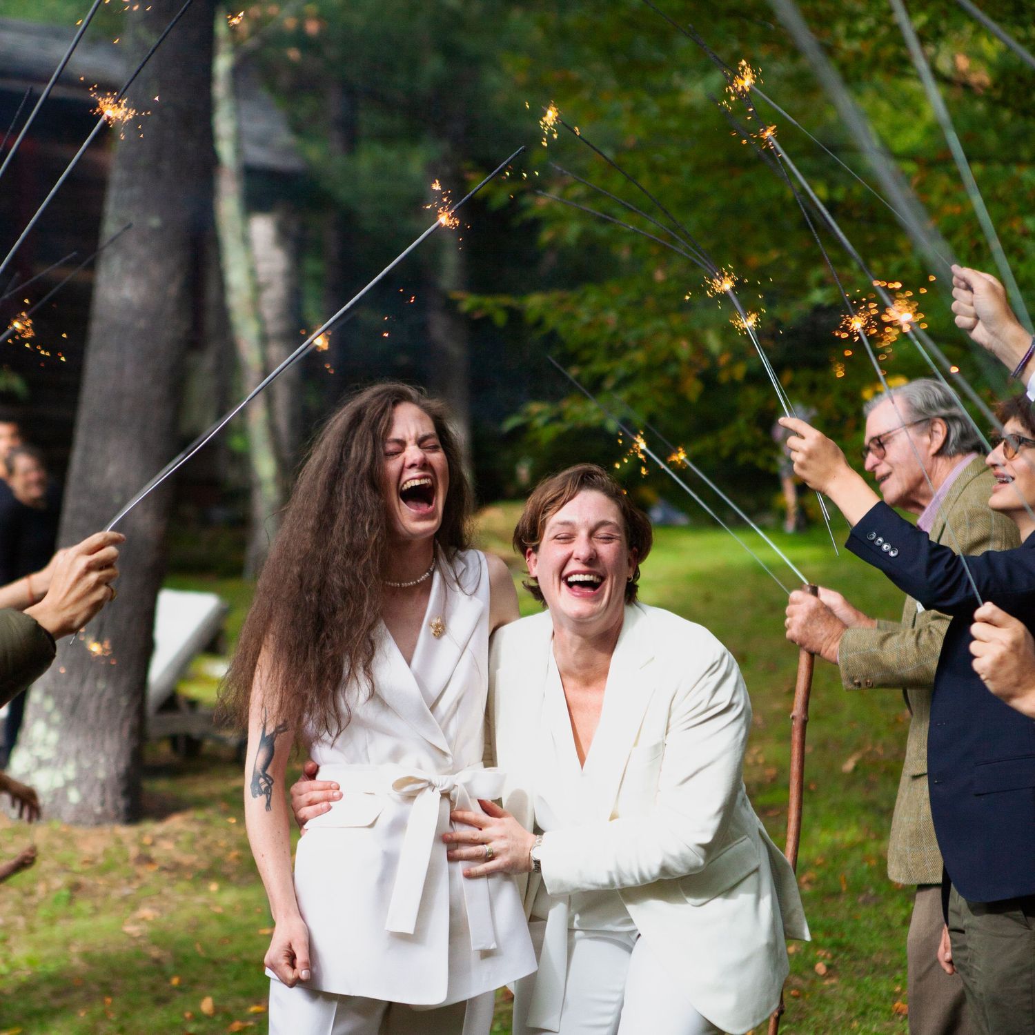 Wedding guests celebrate with sparklers during an outdoor reception.