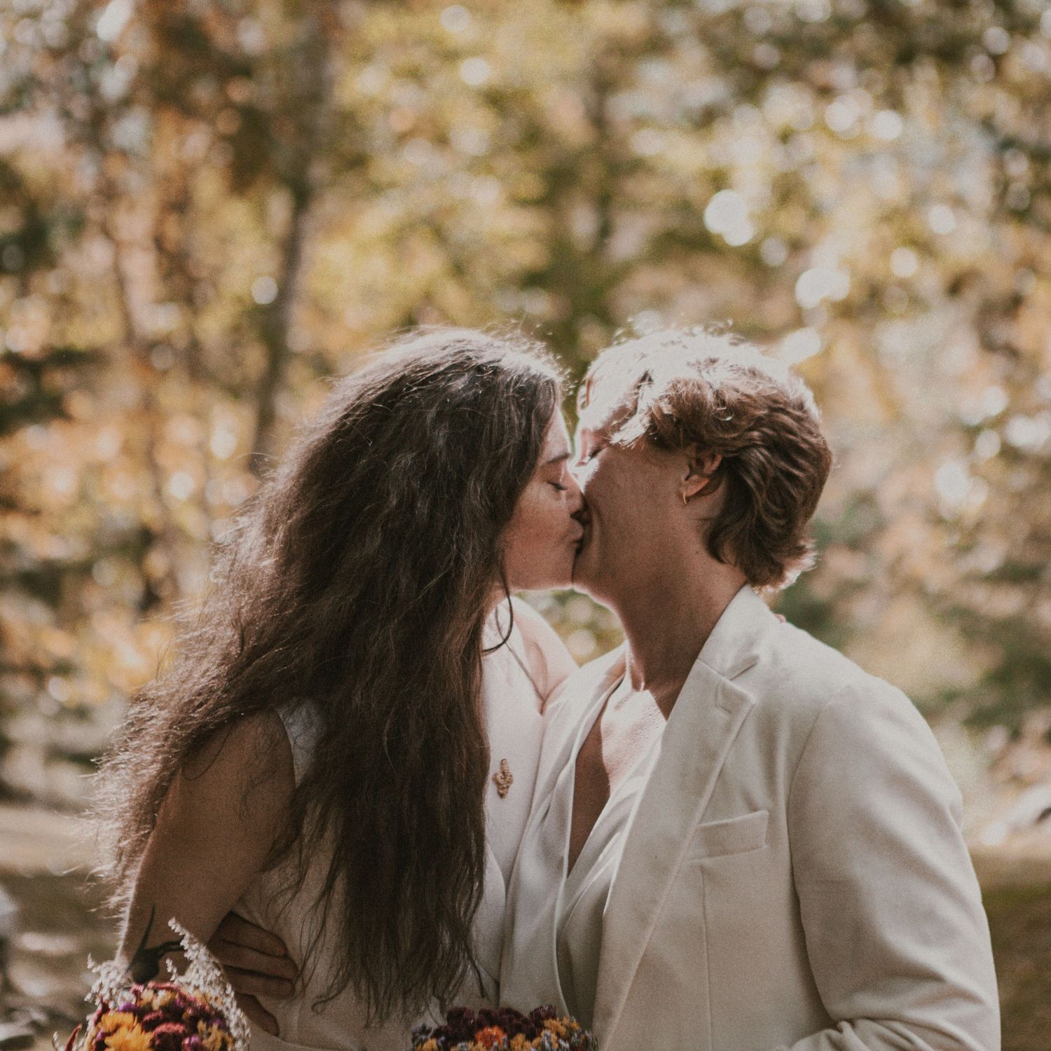 Romantic couple shares intimate moments in white outfits against a natural outdoor backdrop.