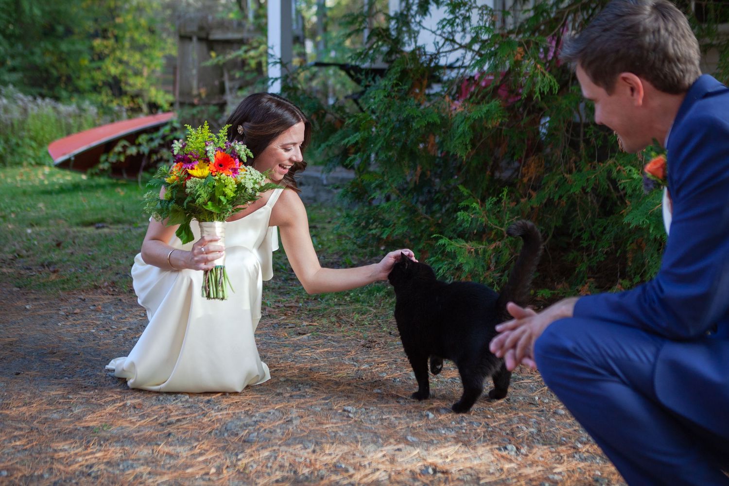 A black dog joins a couple during their outdoor wedding photoshoot.