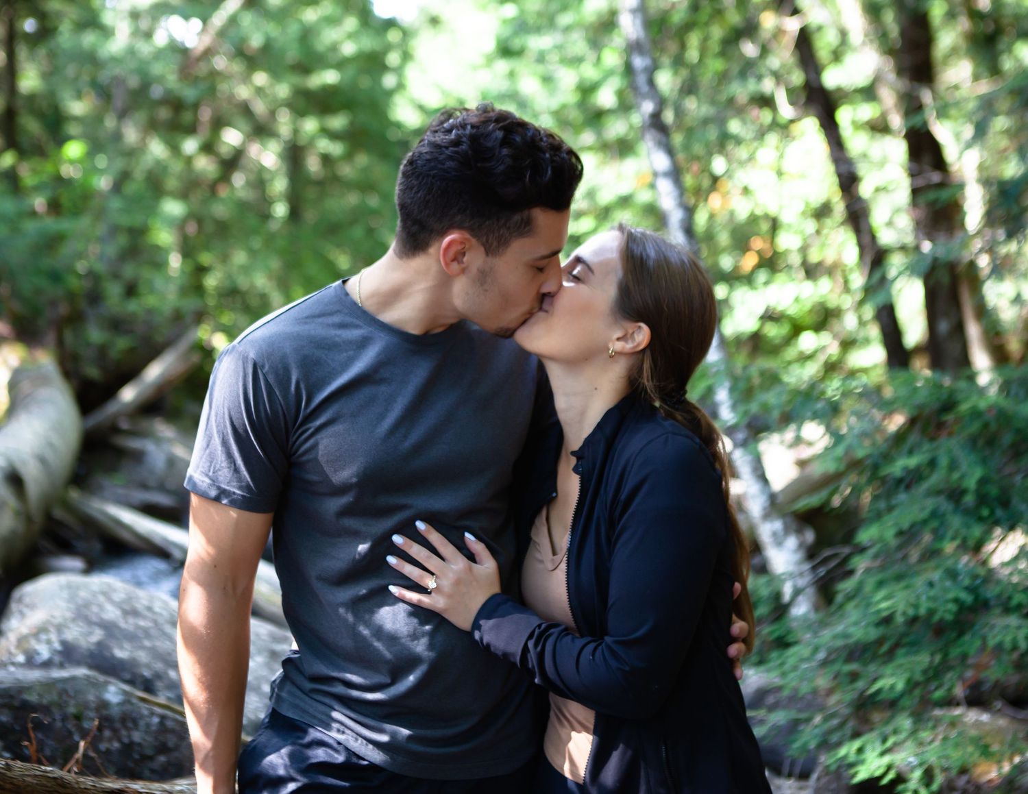 A romantic moment between two people in a wooded setting.