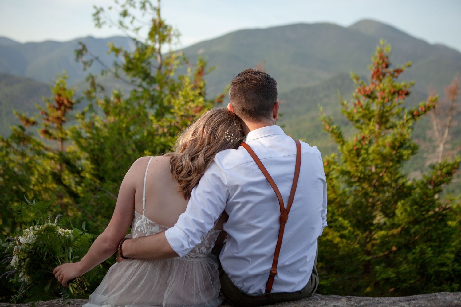 A couple walks hand in hand along a mountain path with autumn foliage.