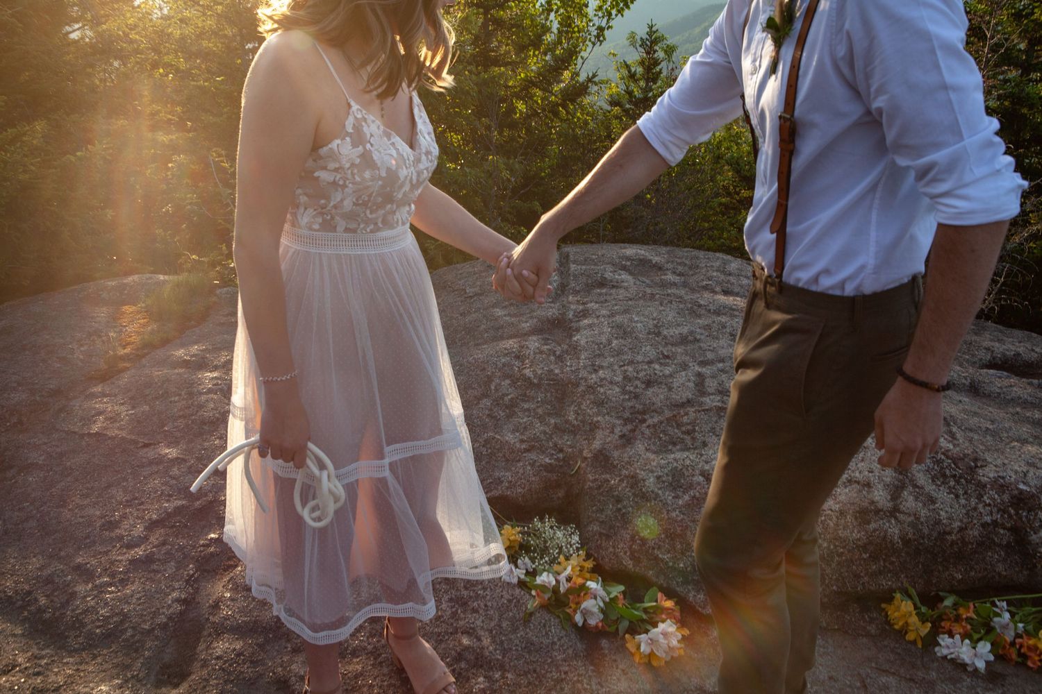 Couple shares romantic moment on rocky overlook during golden hour.