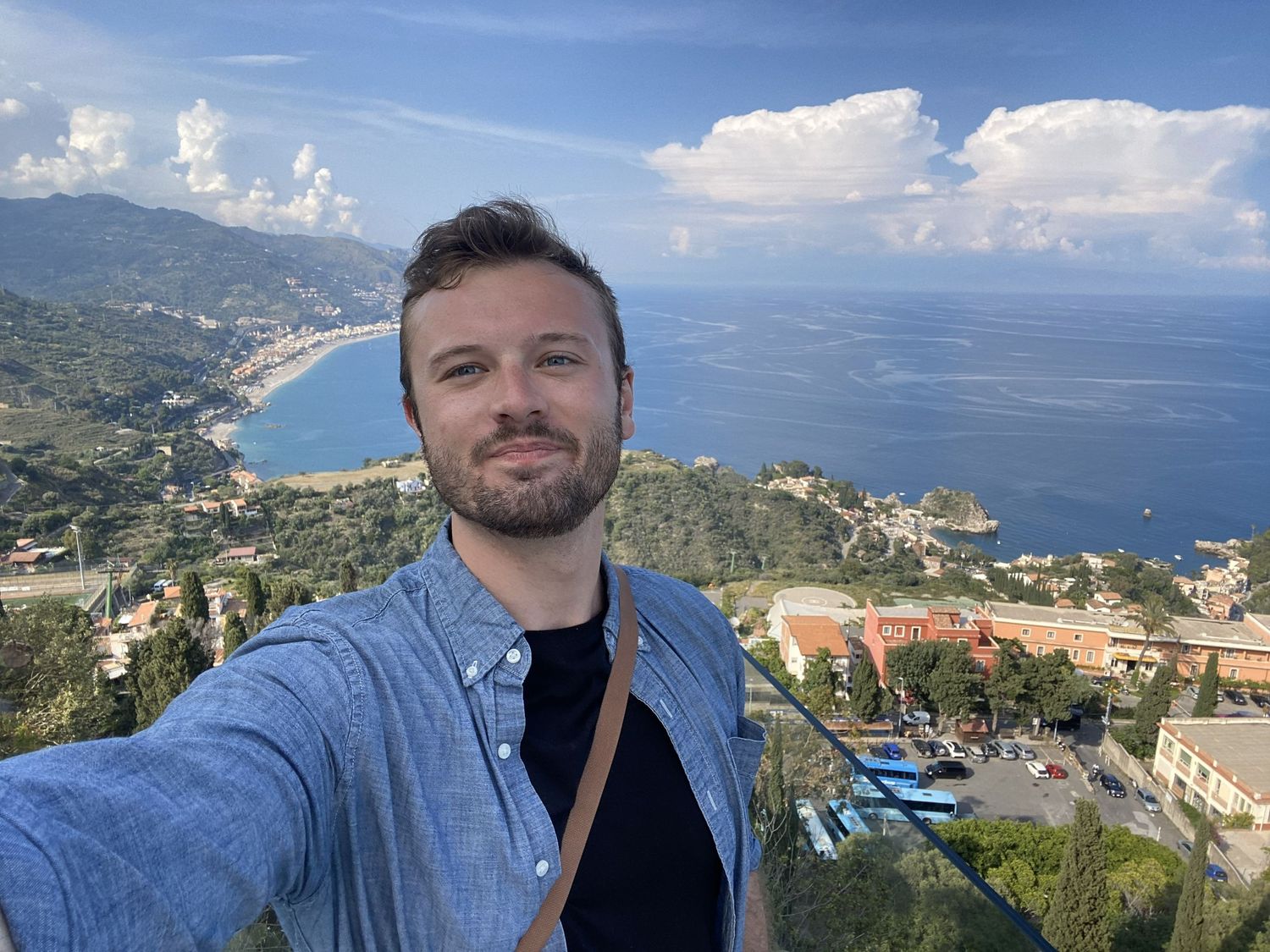 Panoramic view of a coastal town with mountains and blue waters.