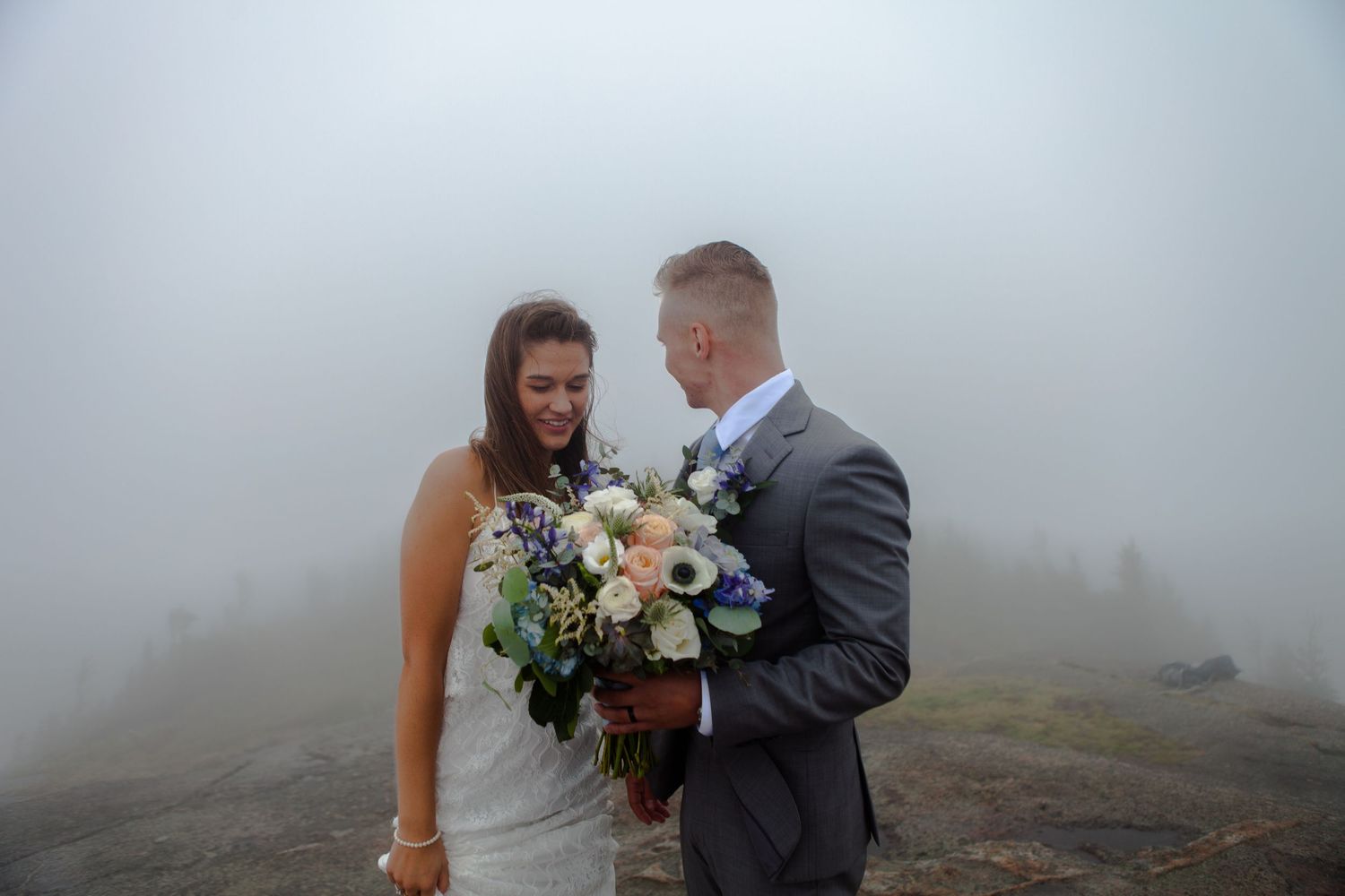 A couple shares a romantic moment in foggy mountain scenery.