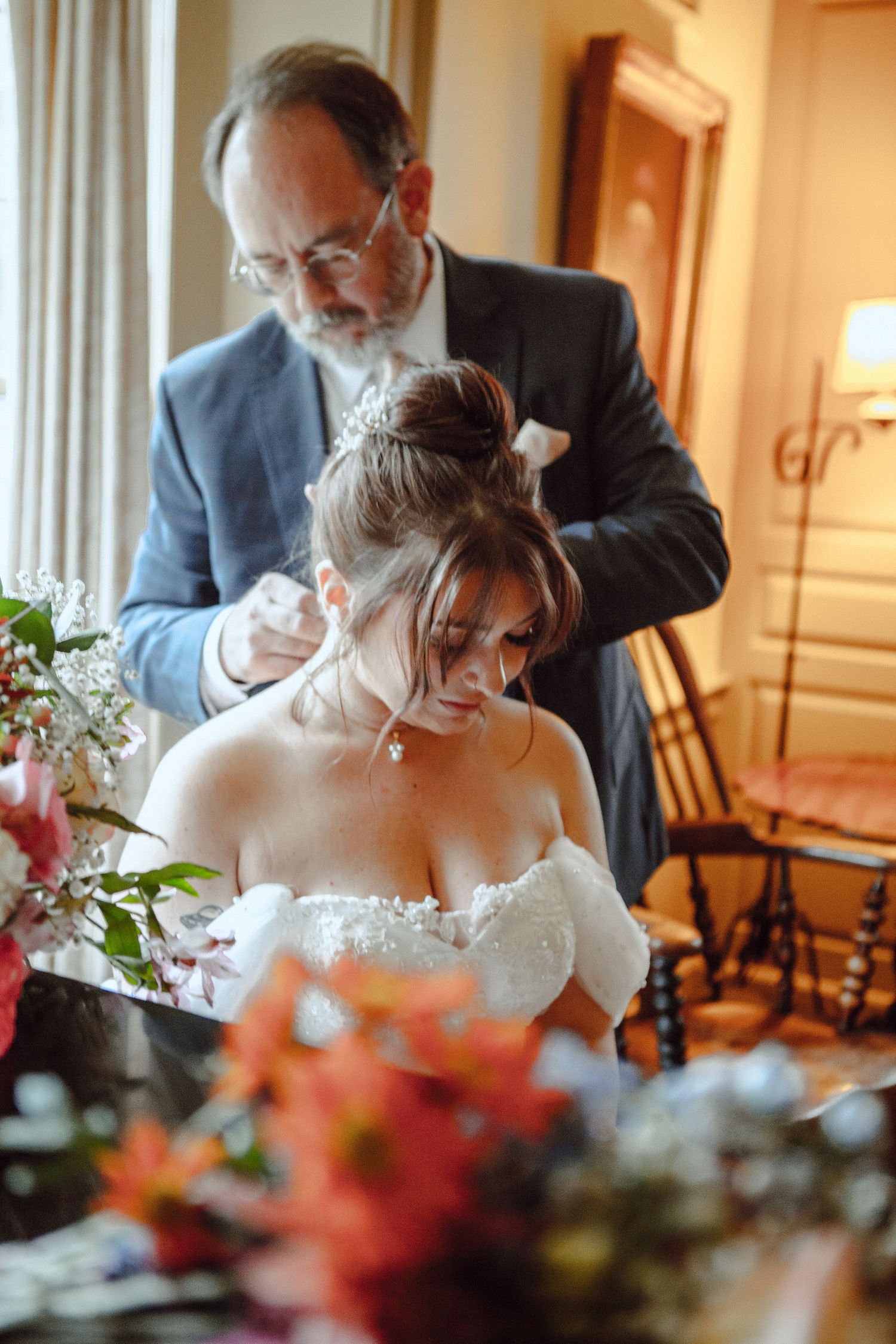 A bride in a white strapless dress gets her hair styled before the wedding ceremony.