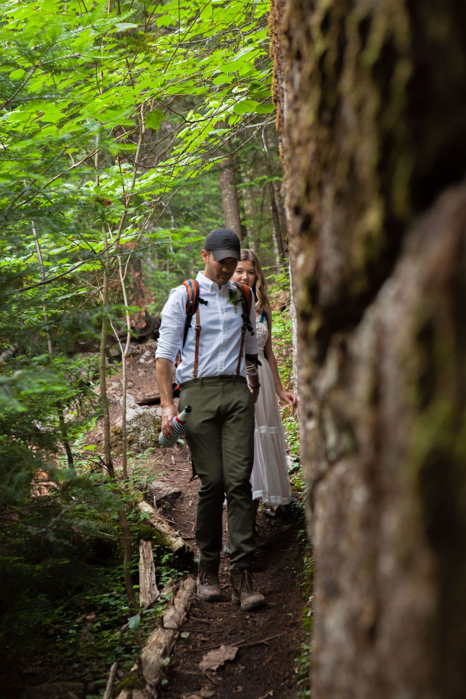 Couple walking together on forest trail through lush green woods.
