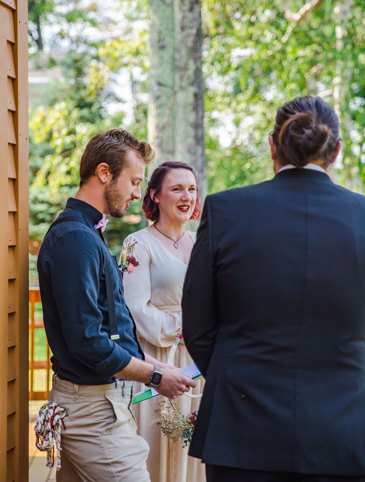 A joyful outdoor wedding celebration with guests gathered under wooden beams.