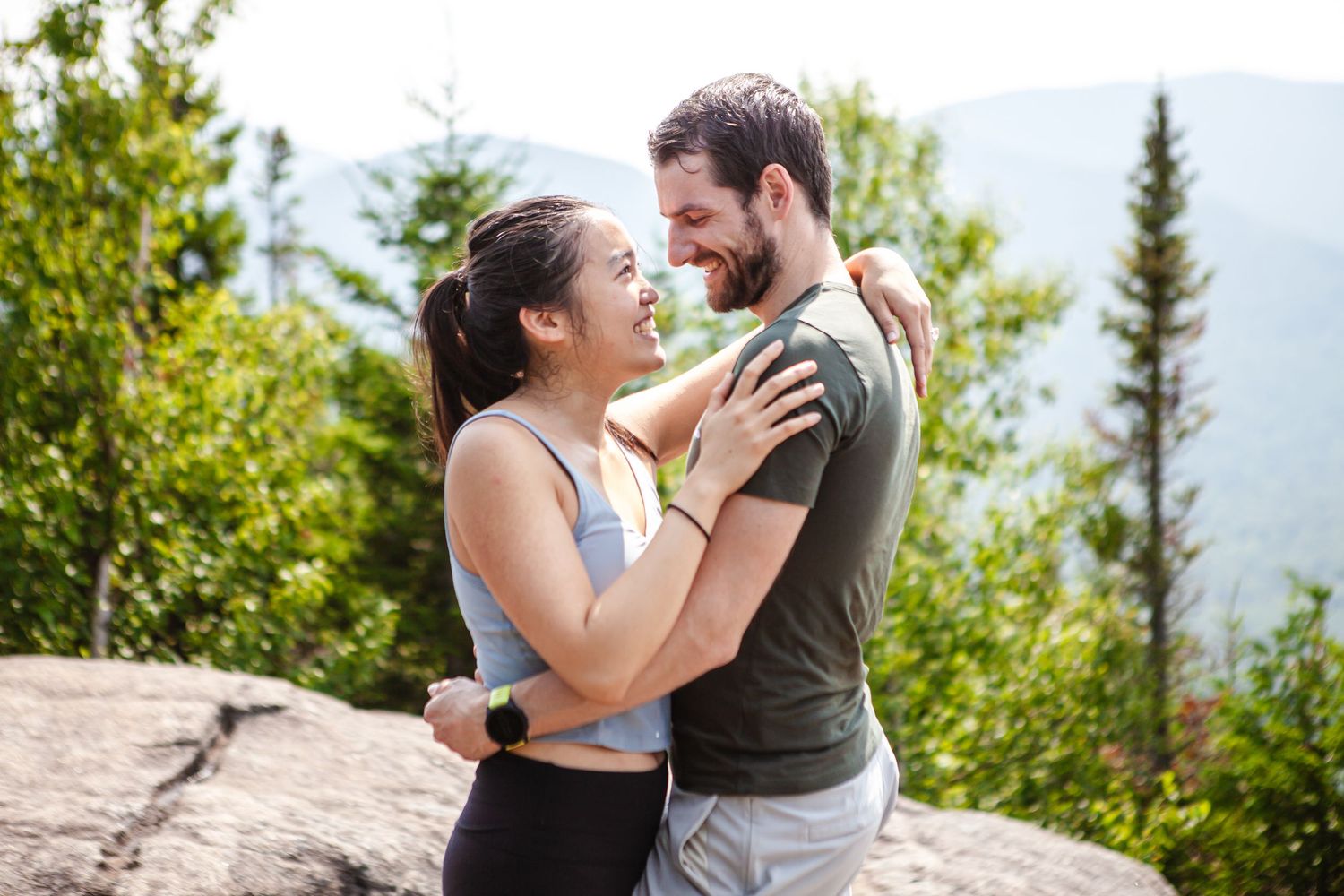 A couple shares an intimate moment on a scenic mountain overlook.