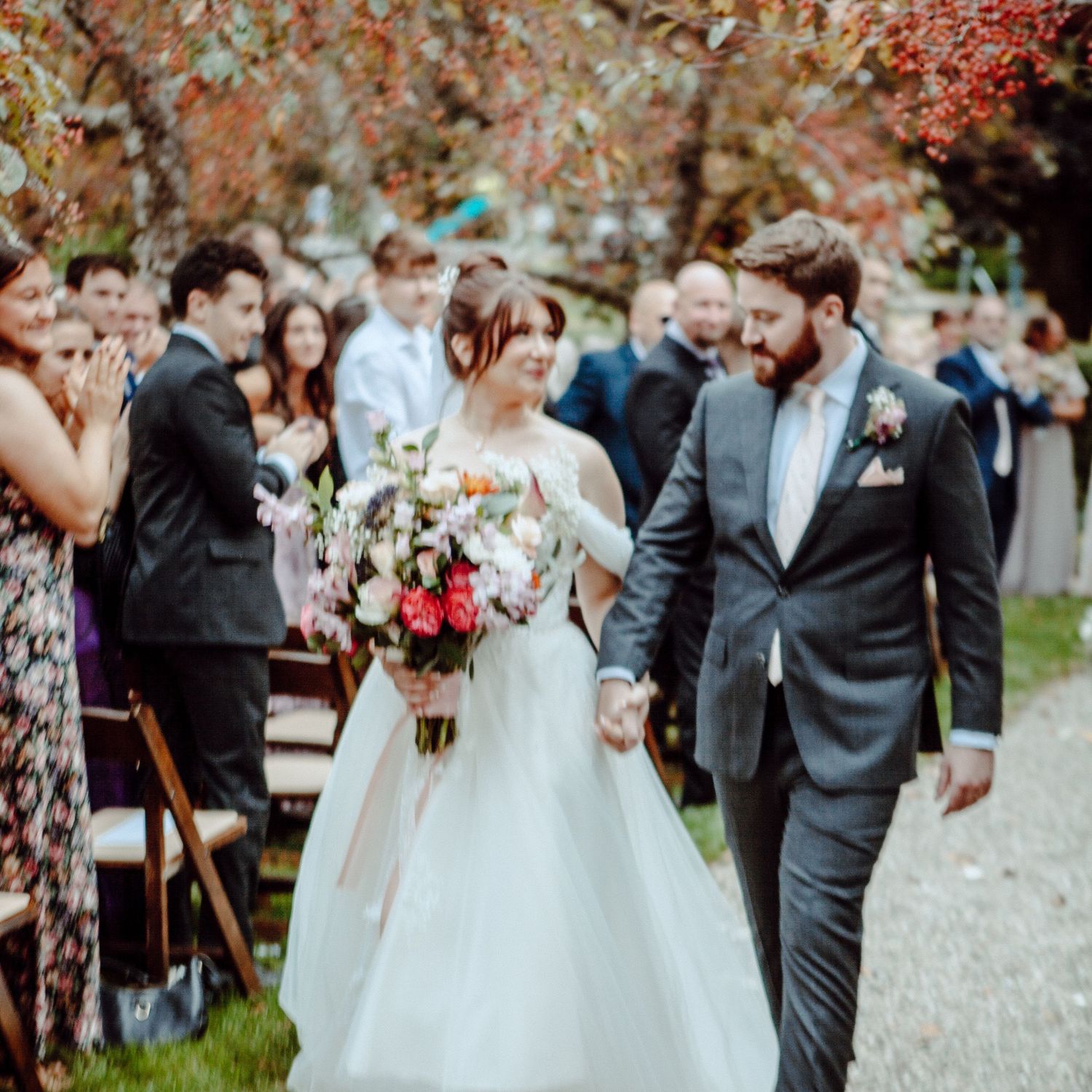 A bride and groom walk down the aisle during their fall outdoor wedding ceremony.