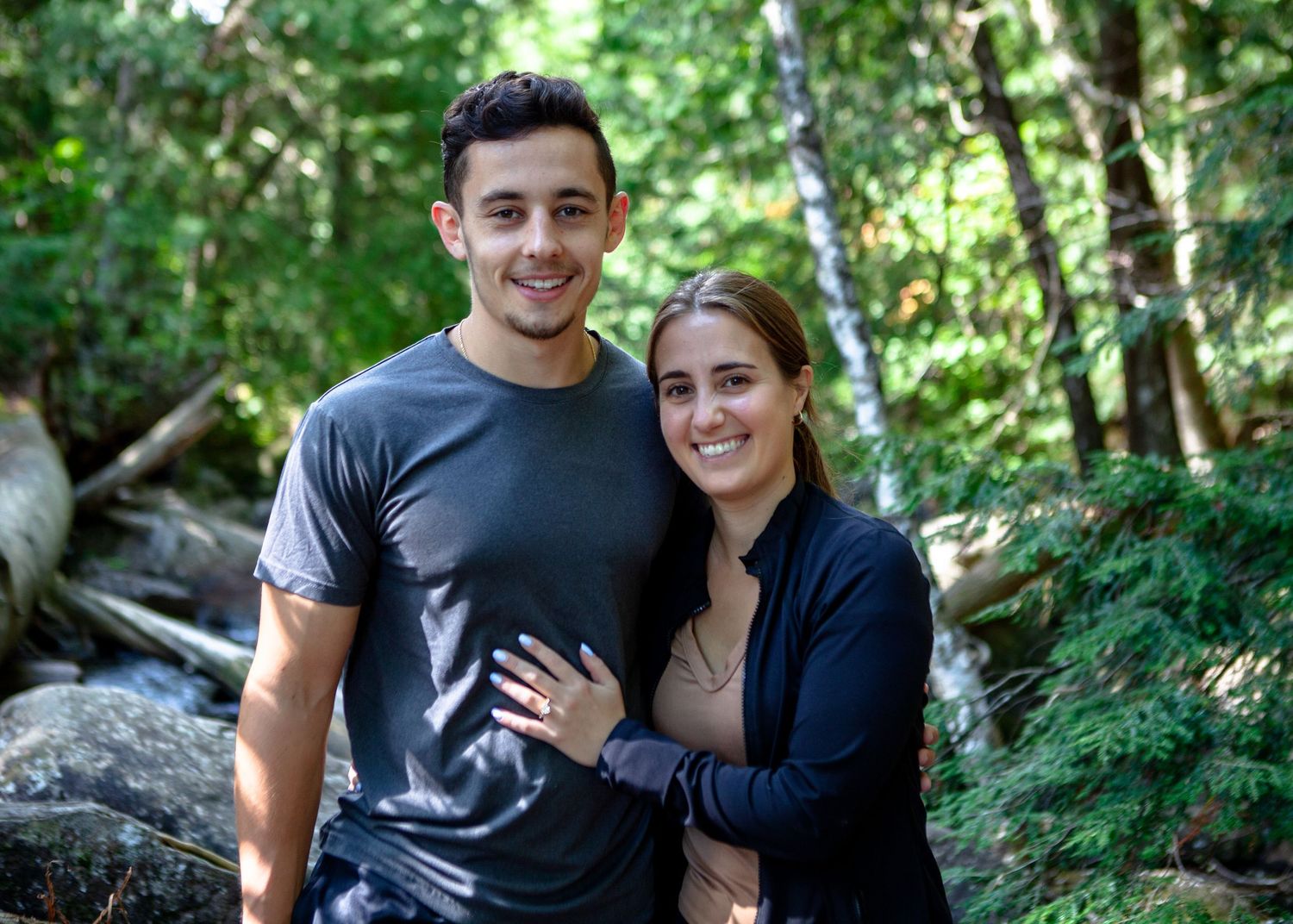 Casual engagement photos in lush green forest setting.